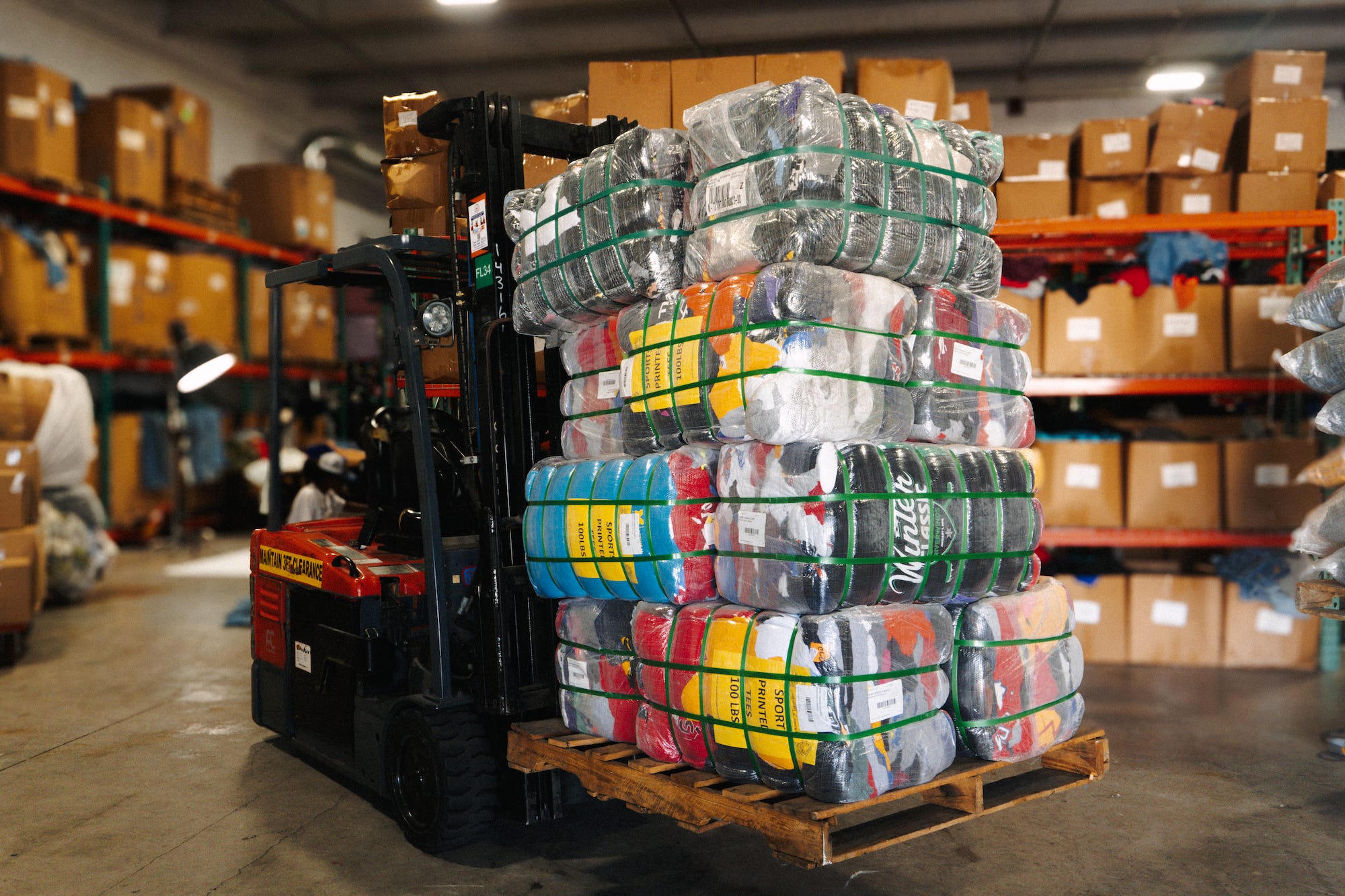 Pallets of clothing on a forklift at the Thrift Vintage Fashion warehouse.