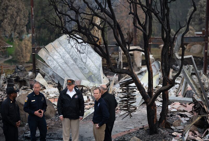 President Donald Trump stands in the middle of what remains of a house, burned from the wildfires in Malibu, California, in 2018.