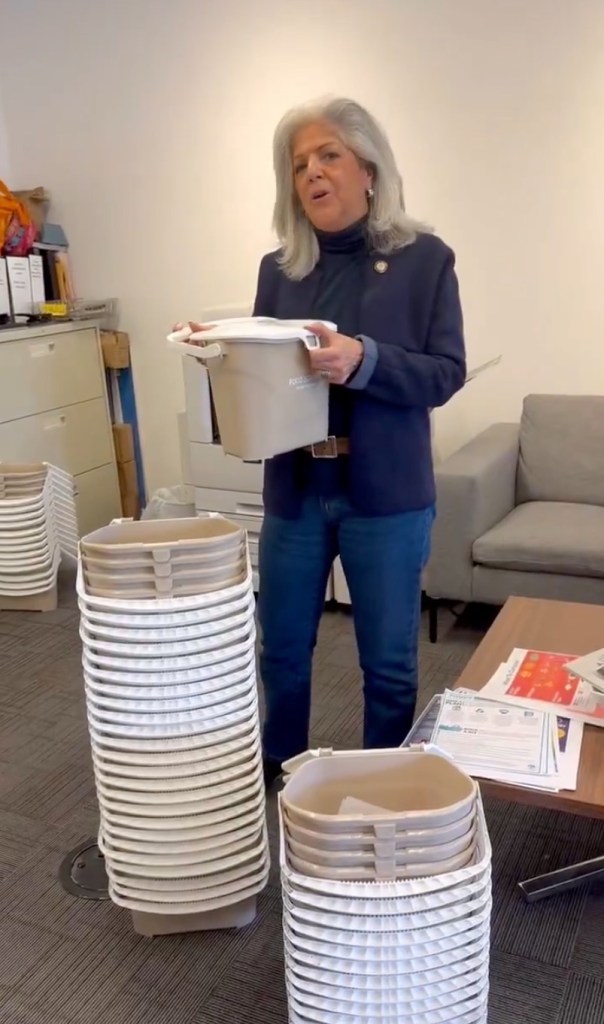 Councilwoman Vickie Paladino discussing countertop composting pails in her office, screenshot from X video. Stacks of pails seen next to her.
