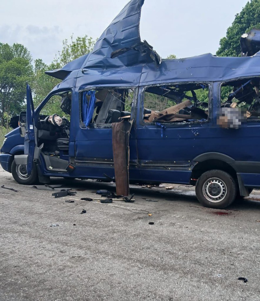 Ukrainian rescuers remove the bodies of killed passengers from a destroyed blue shuttle bus following a drone attack near the village of Bilopillya, Sumy region, amid the Russian invasion of Ukraine. Debris seen scattered and bodies blurred out.