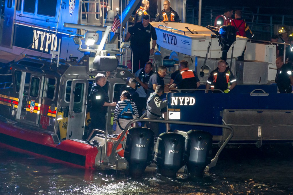 NYPD personnel work to rescue crew members from the boat.