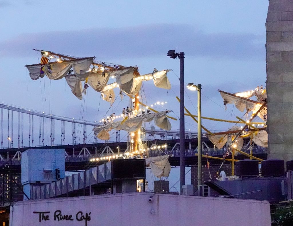 Crew members hand onto to the damaged masts of the training ship after the vessel struck the Brooklyn Bridge.