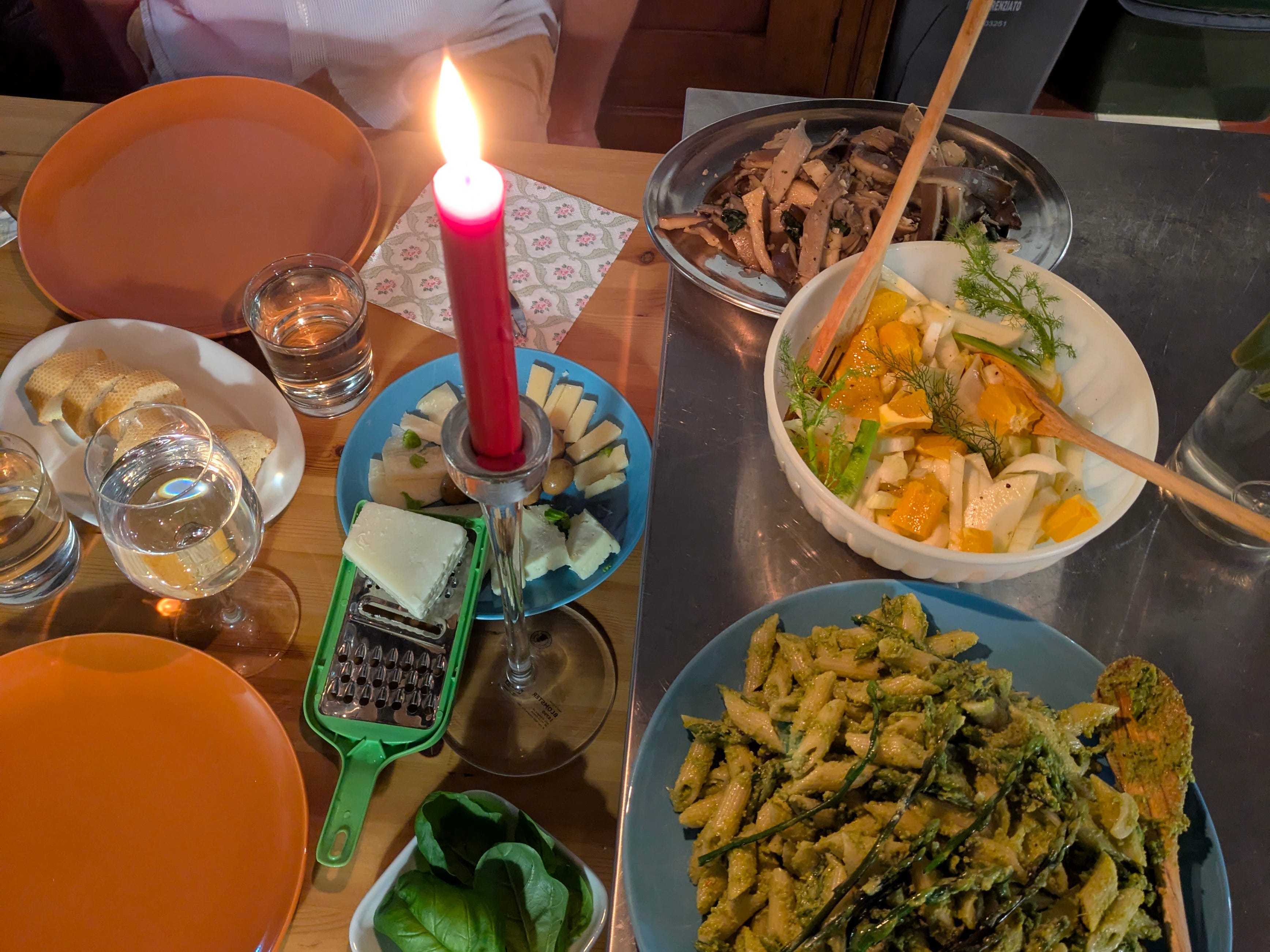 A table with a colorful meal of vegetables and pasta and a candle.