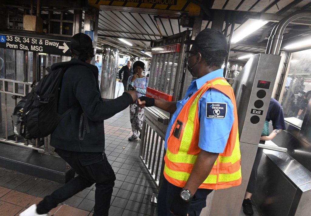 Allied Guard Romuald Zampou standing at the emergency gate watching straphangers go through it