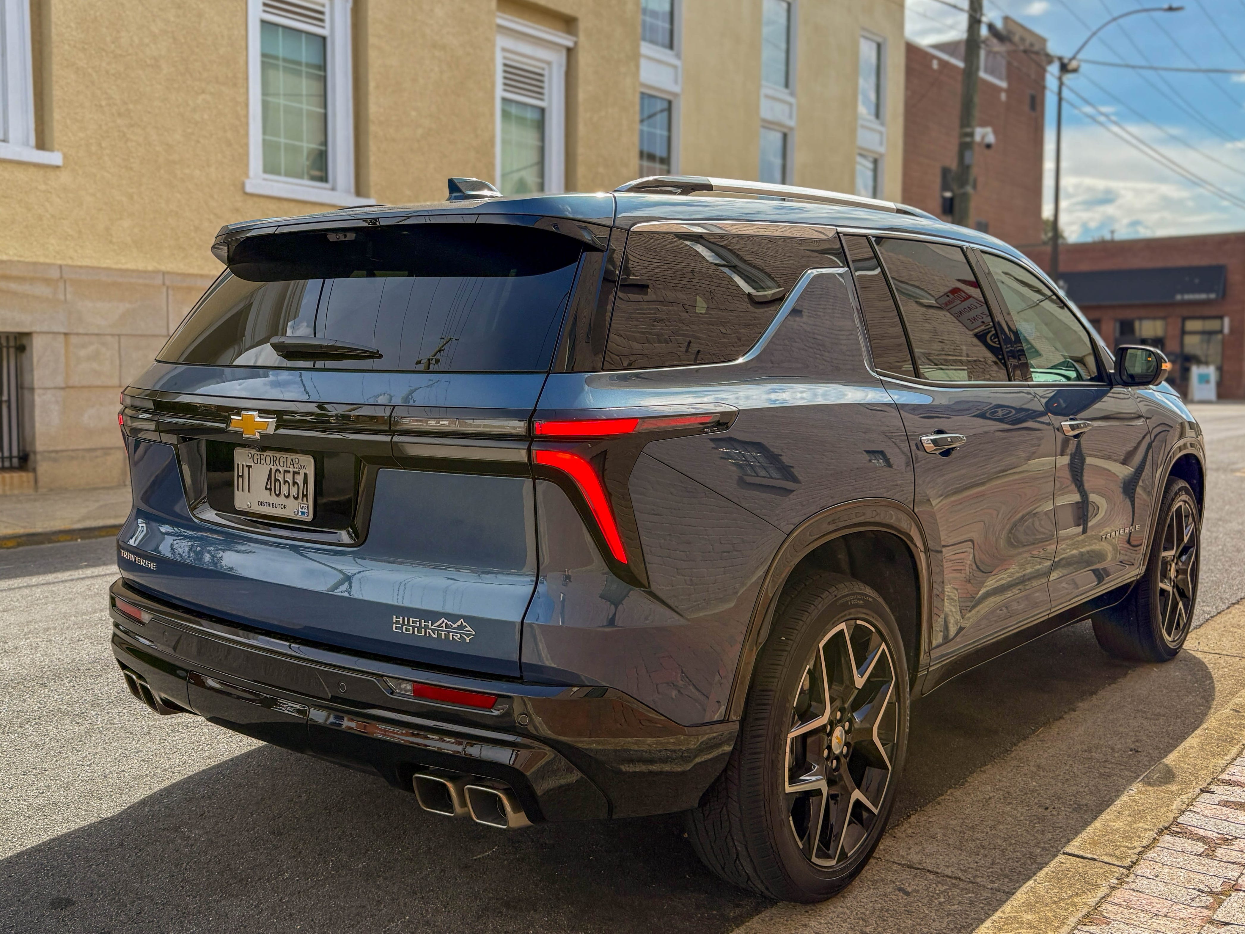 The right rear of a blue 2025 Chevrolet Traverse High Country midsize family SUV parked on the street.