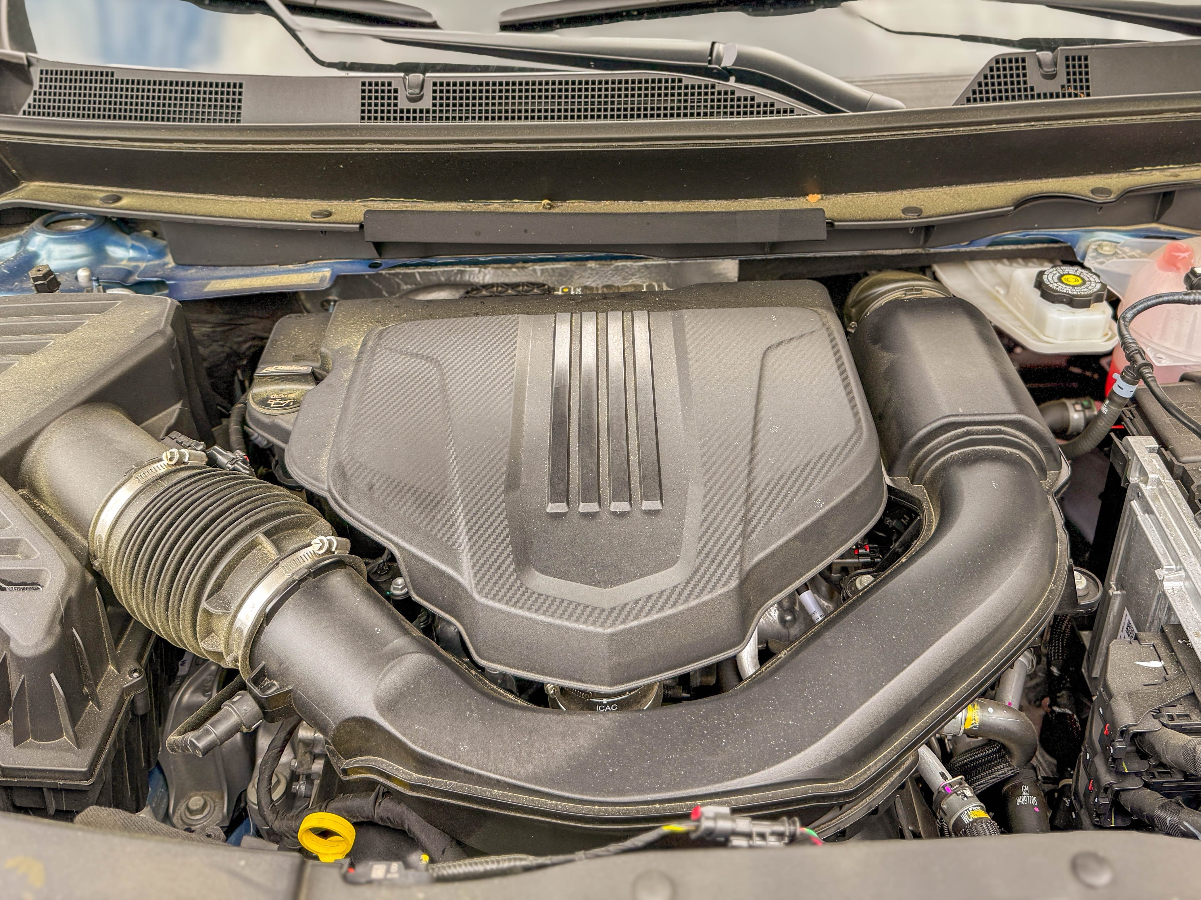 The 2.5-liter, turbocharged four-cylinder engine under the open hood of a blue 2025 Chevrolet Traverse High Country midsize family SUV.