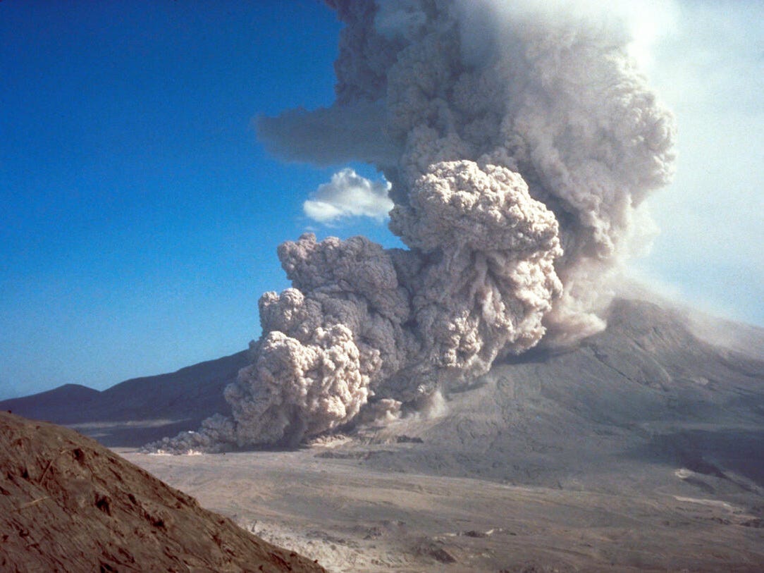 A pyroclastic flow of gas and debris pouring out of Mount St. Helens in a large brownish-white cloud