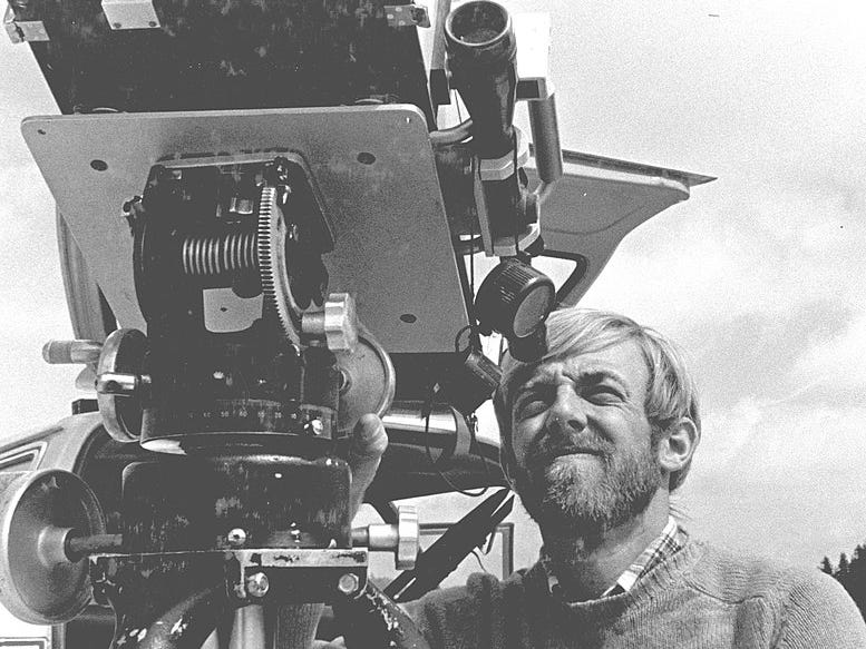 A man with a beard looks through a large piece of equipment