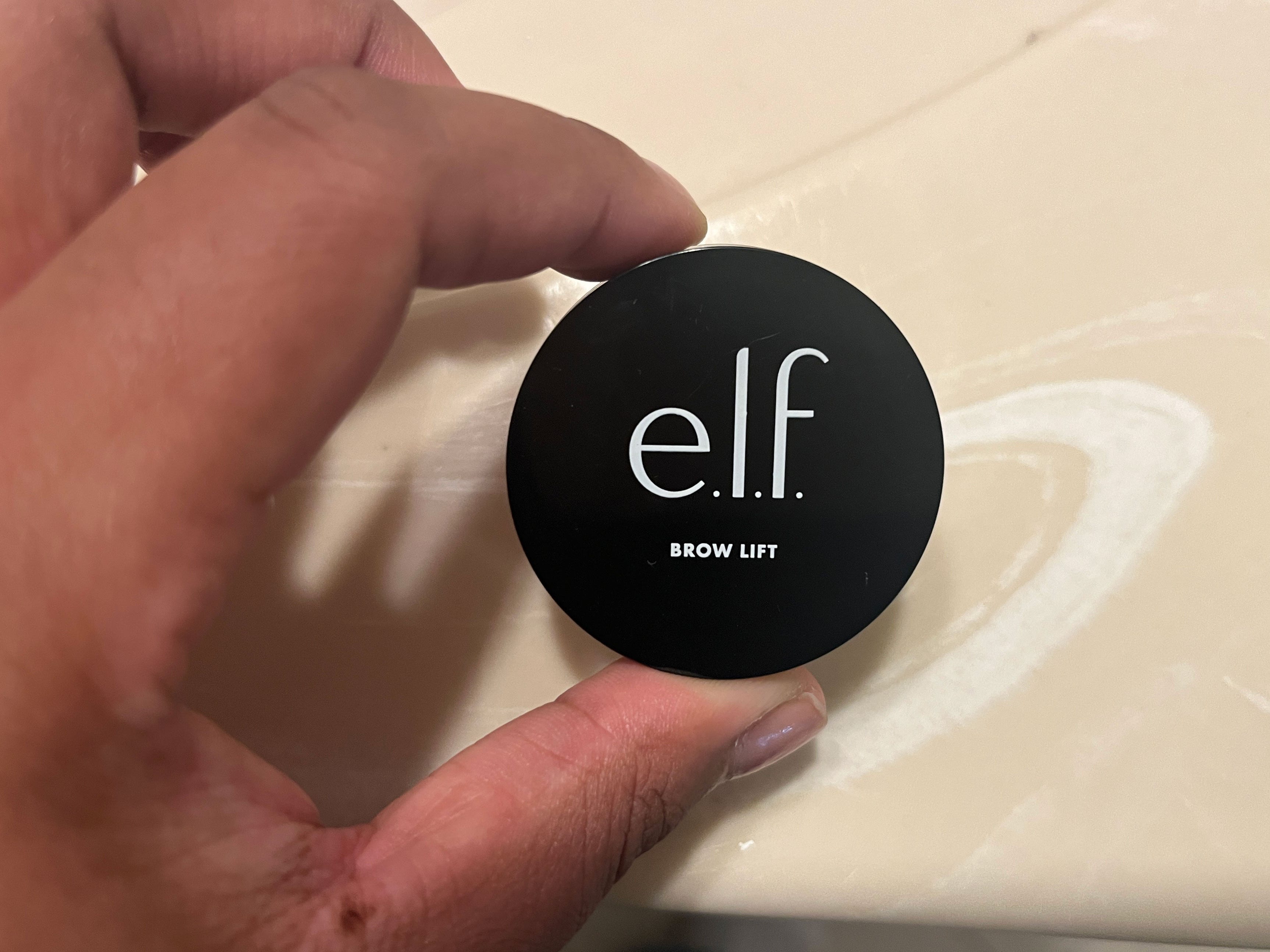 A woman's hand holding a small container marked