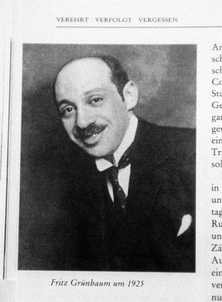 A black and white photo of a man with a mustache. 