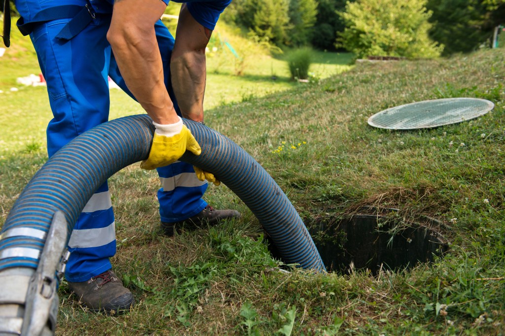 Worker emptying and cleaning sludge from a household septic tank system