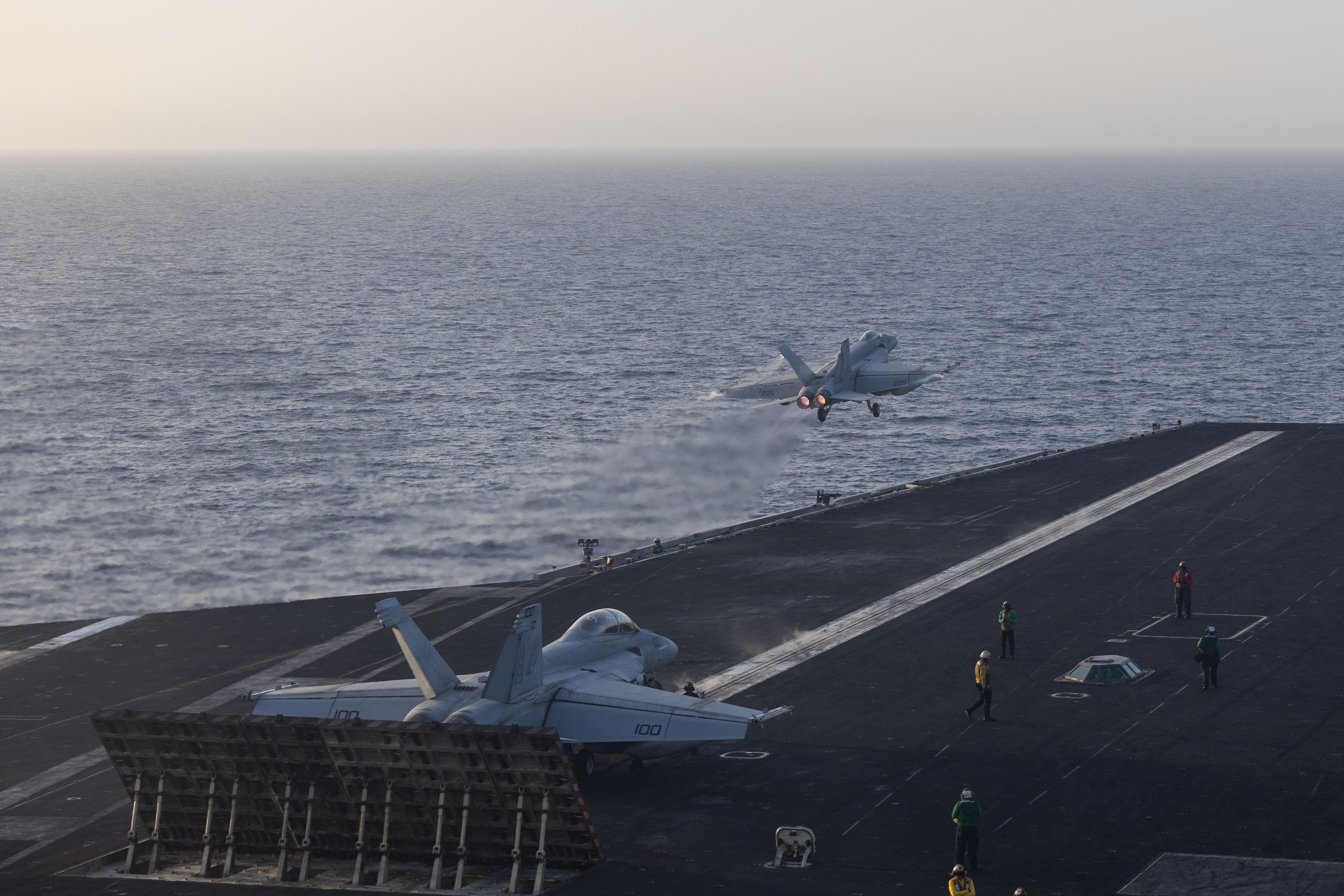 An F/A-18F Super Hornet, attached to Strike Fighter Squadron (VFA) 11, right, prepares for launch as an F/A-18E Super Hornet, attached to Strike Fighter Squadron (VFA) 143, launches from the flight deck of the Nimitz-class aircraft carrier USS Harry S. Truman (CVN 75) during flight operations in the U.S. Central Command area of responsibility.