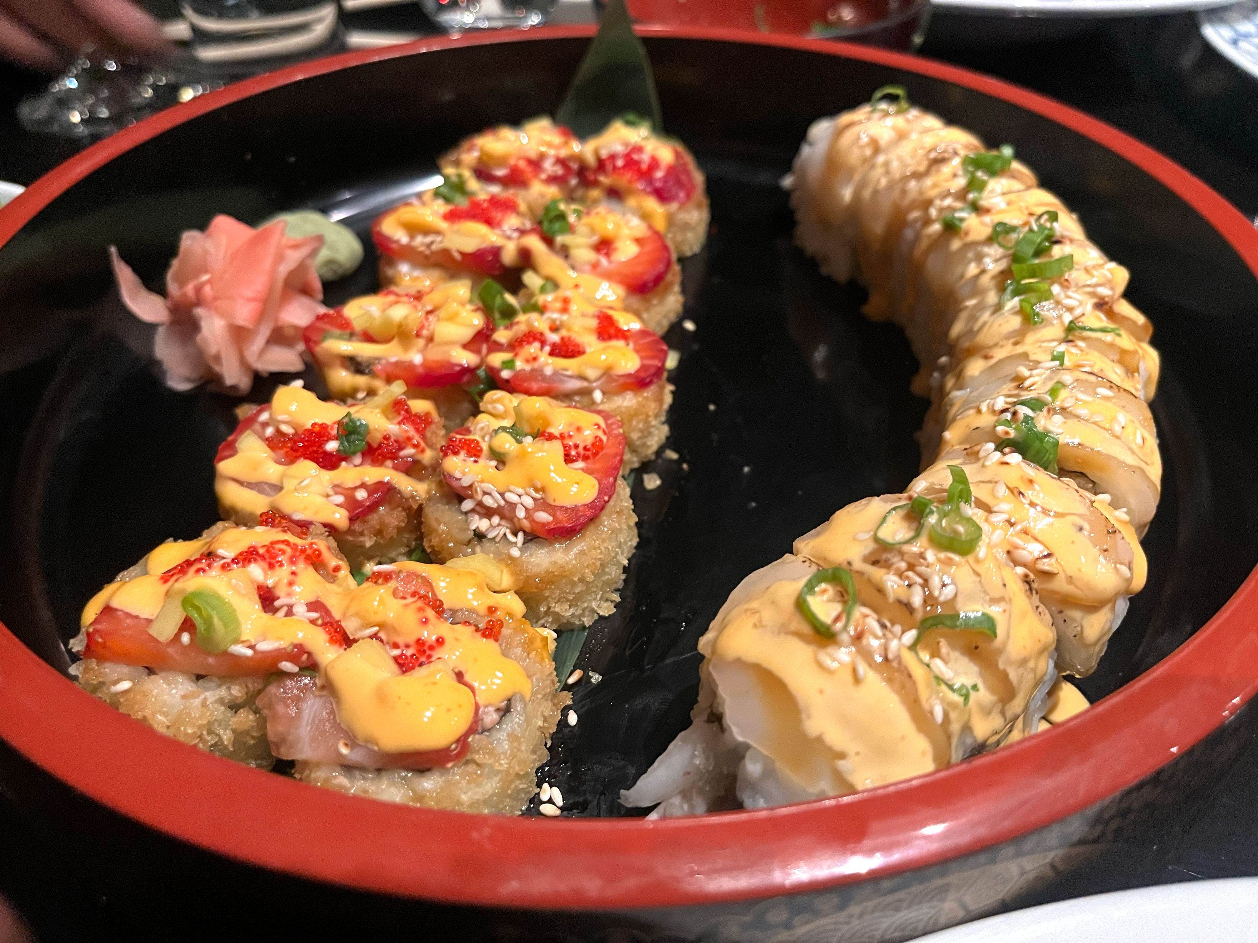 Two different specialty sushi rolls on a large dish.