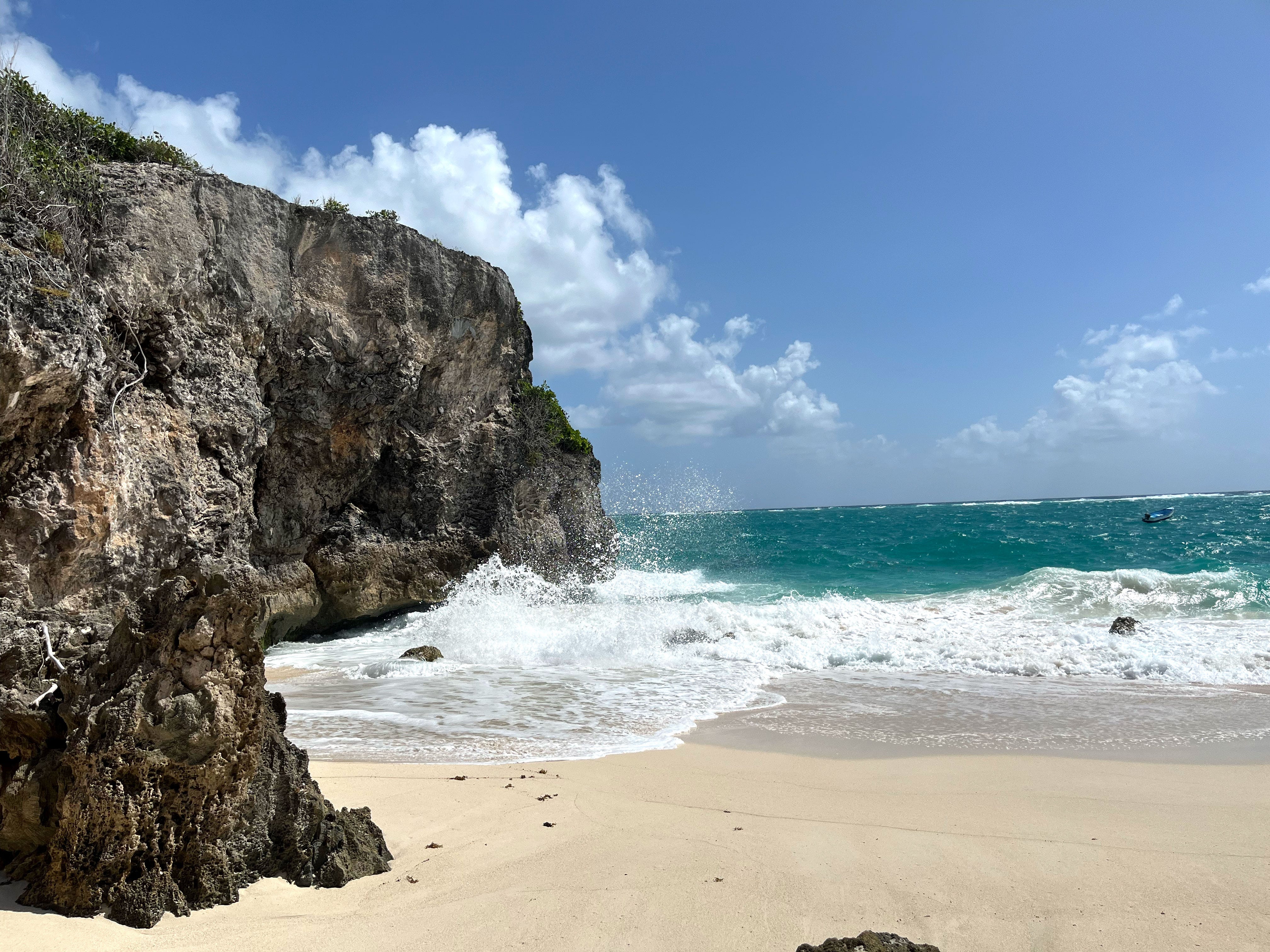 Ocean waves crash against rocks on a beach.