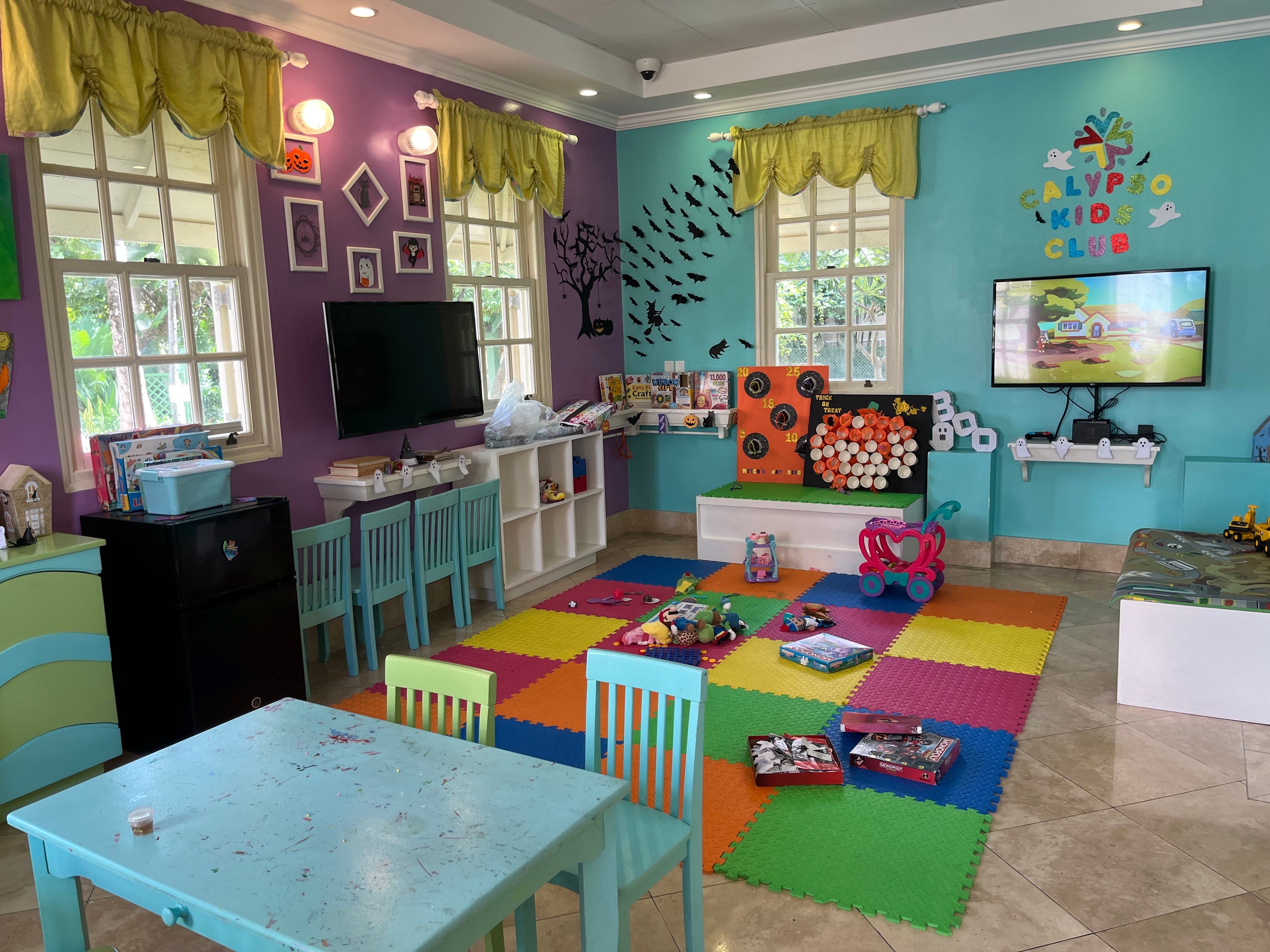 A colorful room with children's toys, a play mat, and colorful tables and chairs.