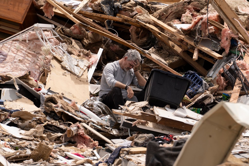 James Sexton emotionally cleaning up debris from his house in Sunshine Hills, Kentucky after a devastating tornado