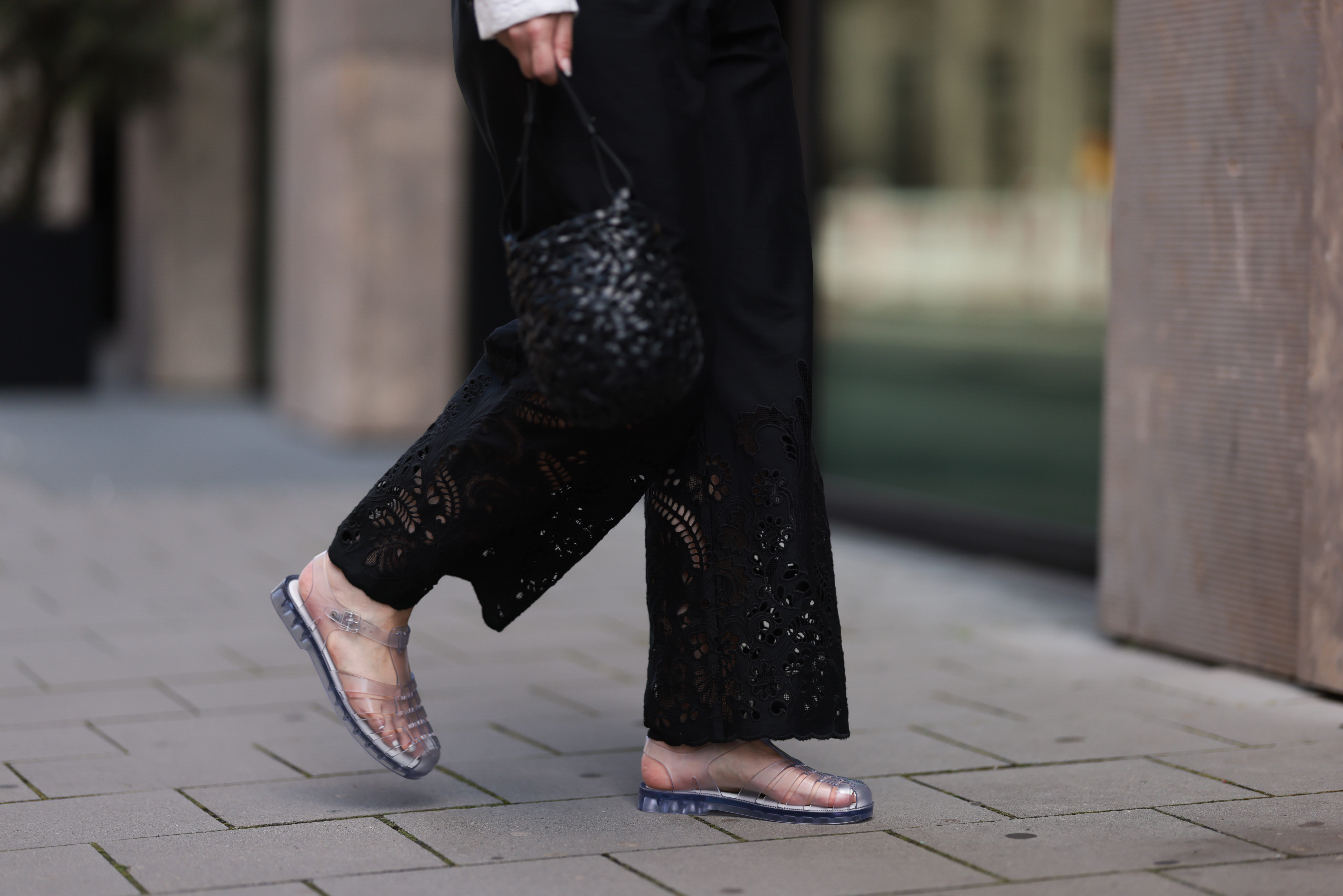 Legs of person wearing Black lace pants and clear fisherman sandals
