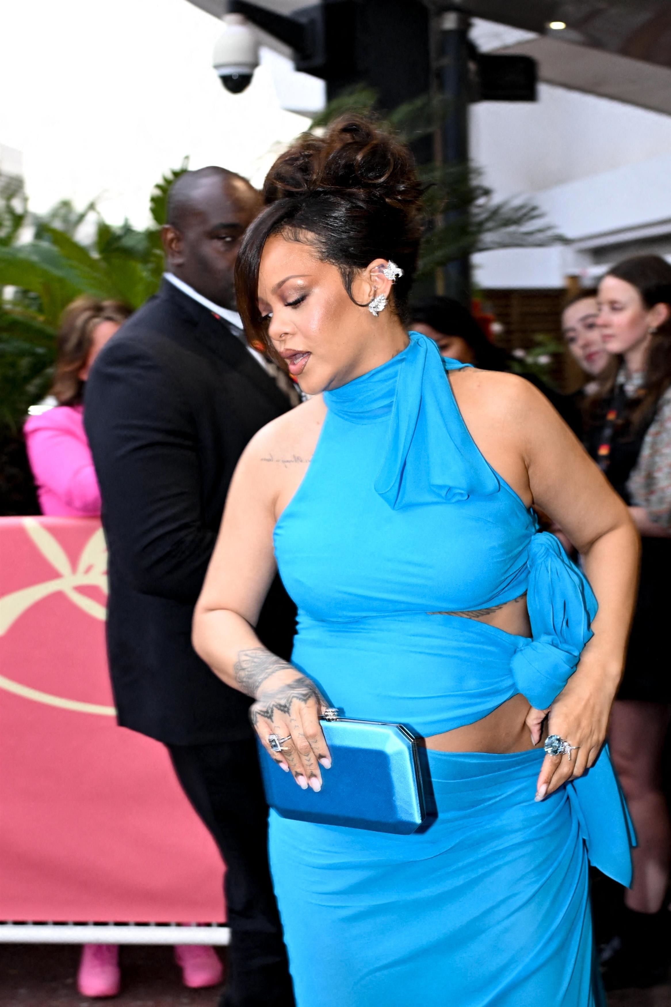 Rihanna with a blue clutch and blue dress at a red carpet event. 