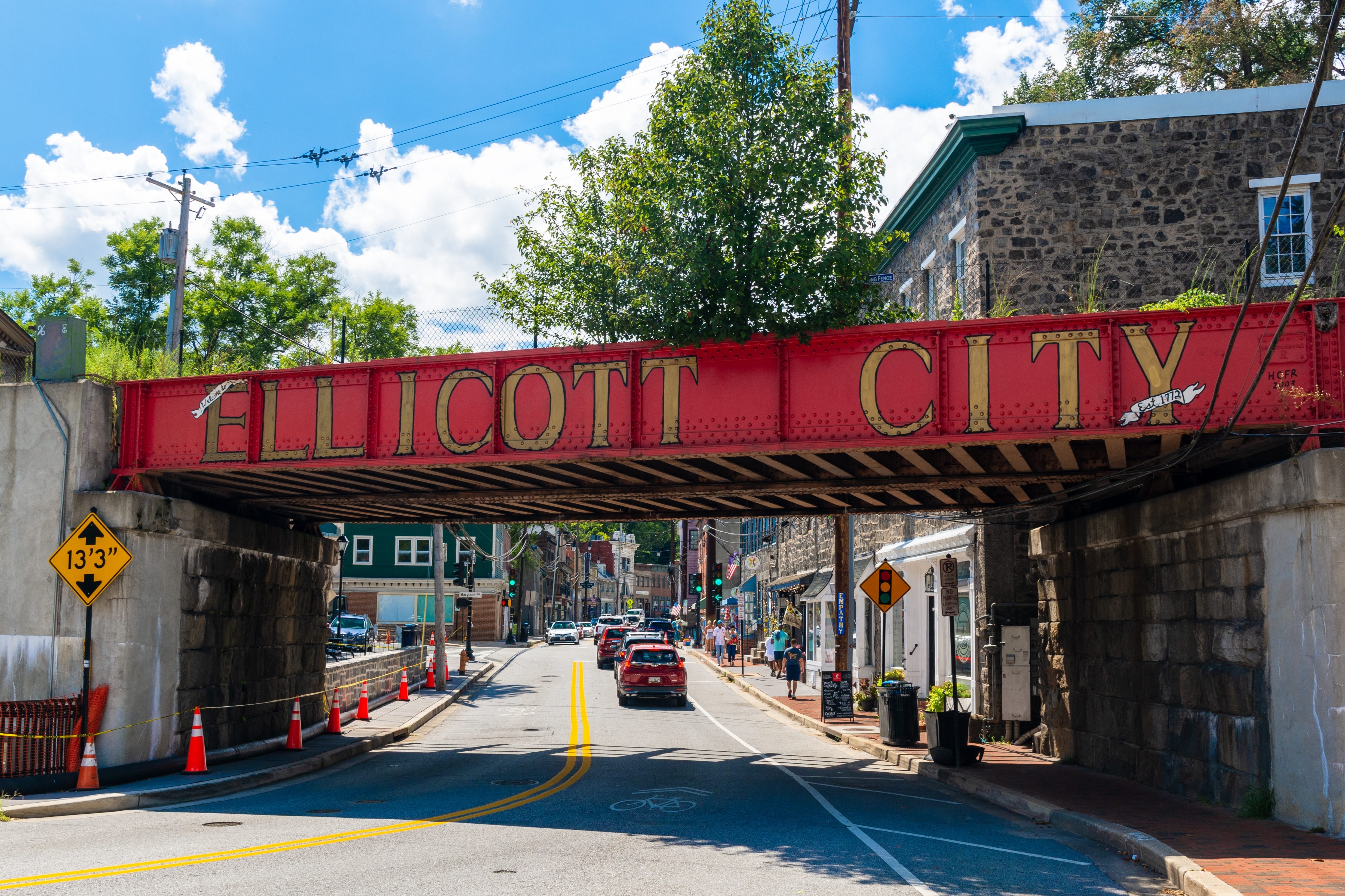 A bridge with a red background reading Ellicott City in front of a downtown area