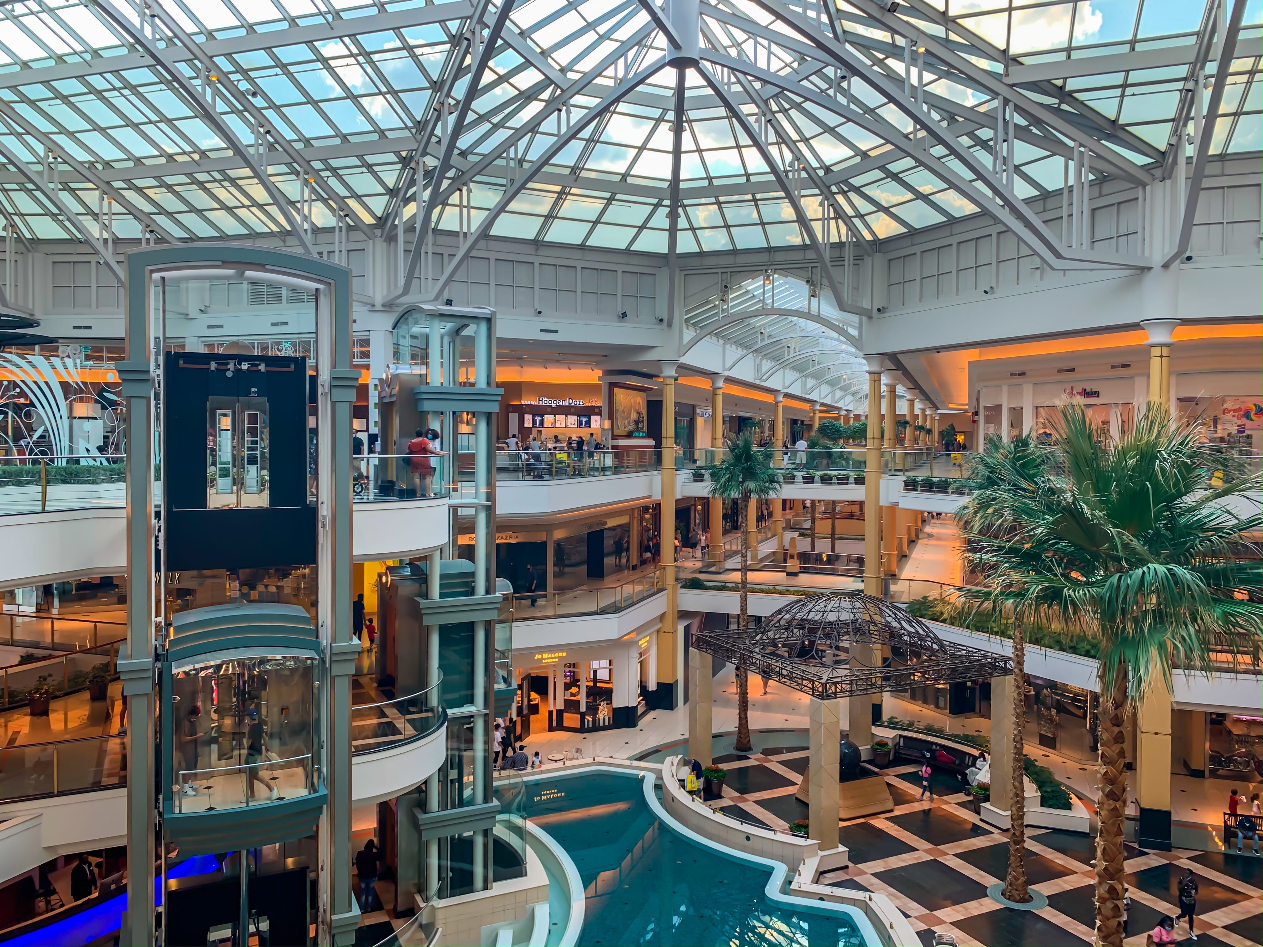 A mall with three floors and a large skylight over a small pool