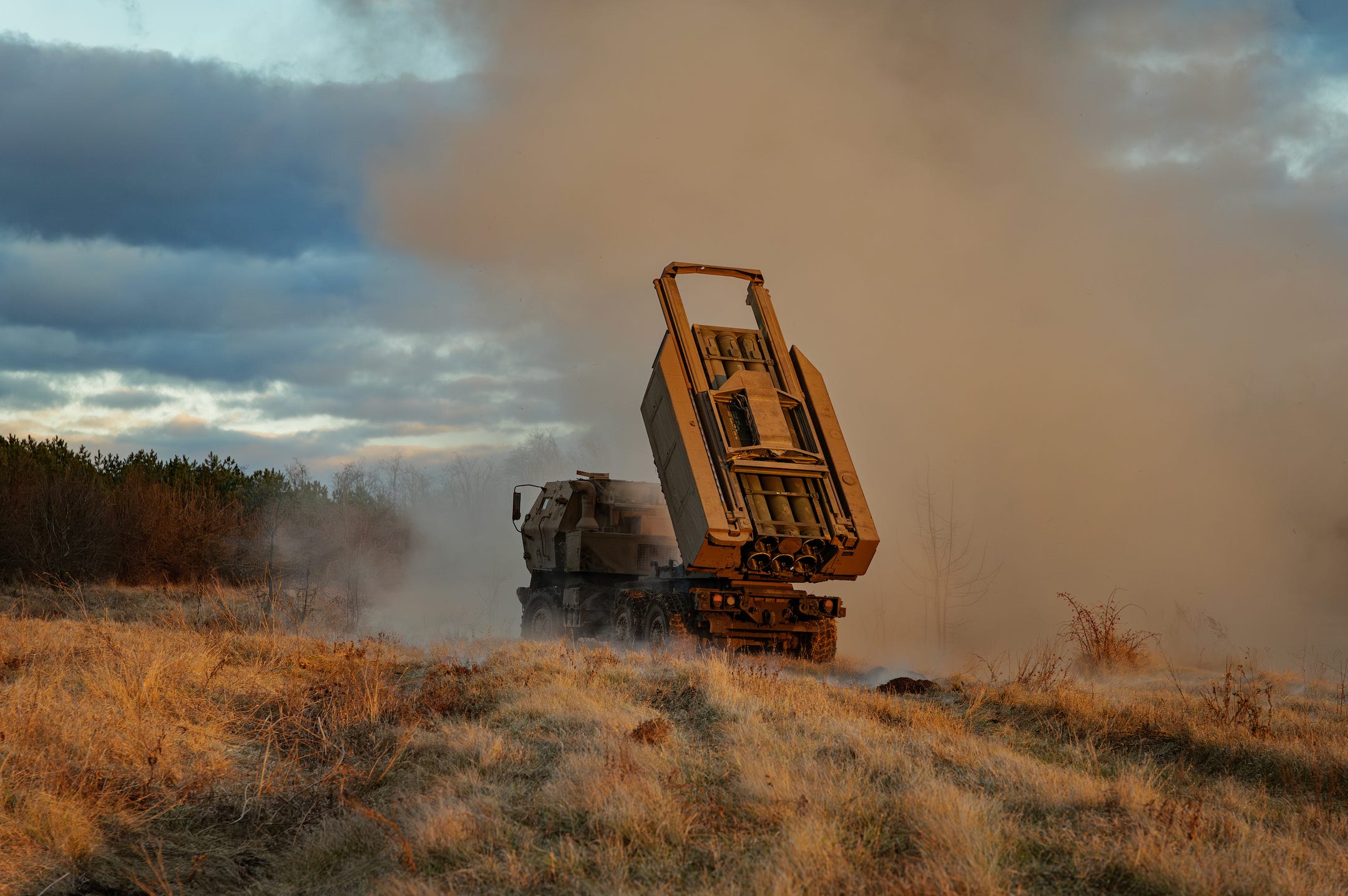 A US-provided M142 HIMARS launching a rocket, surrounded by smoke and dust.