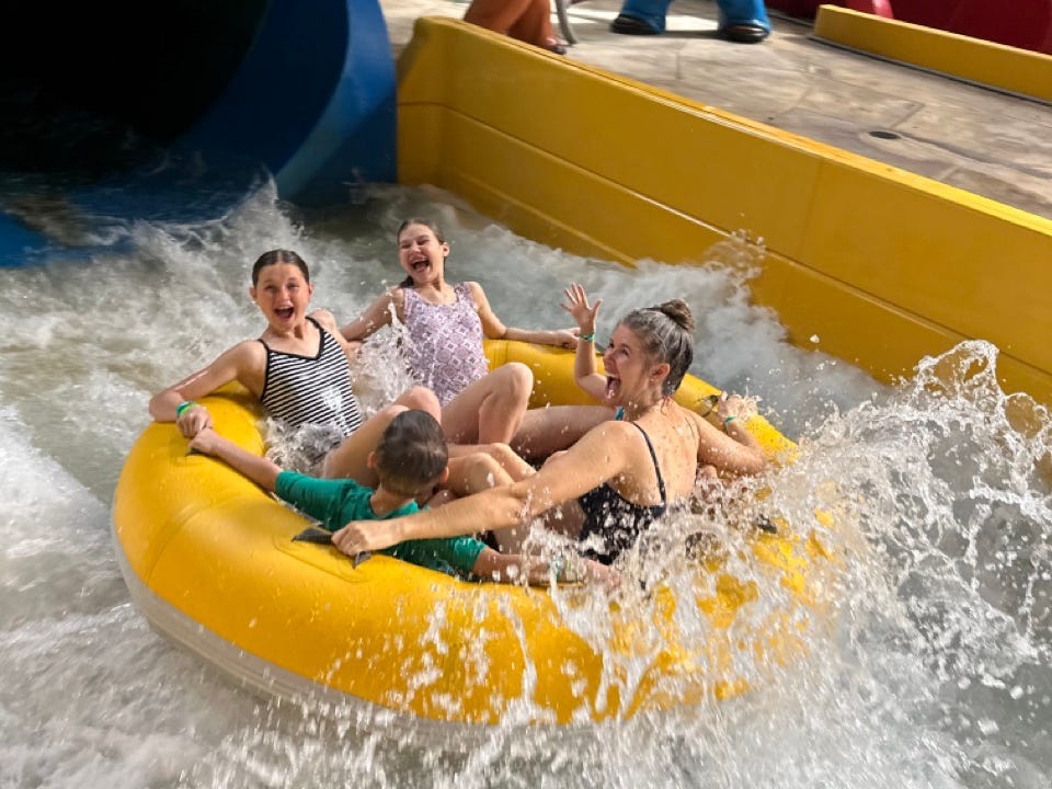 Family smiling on yellow raft tube down waterslide