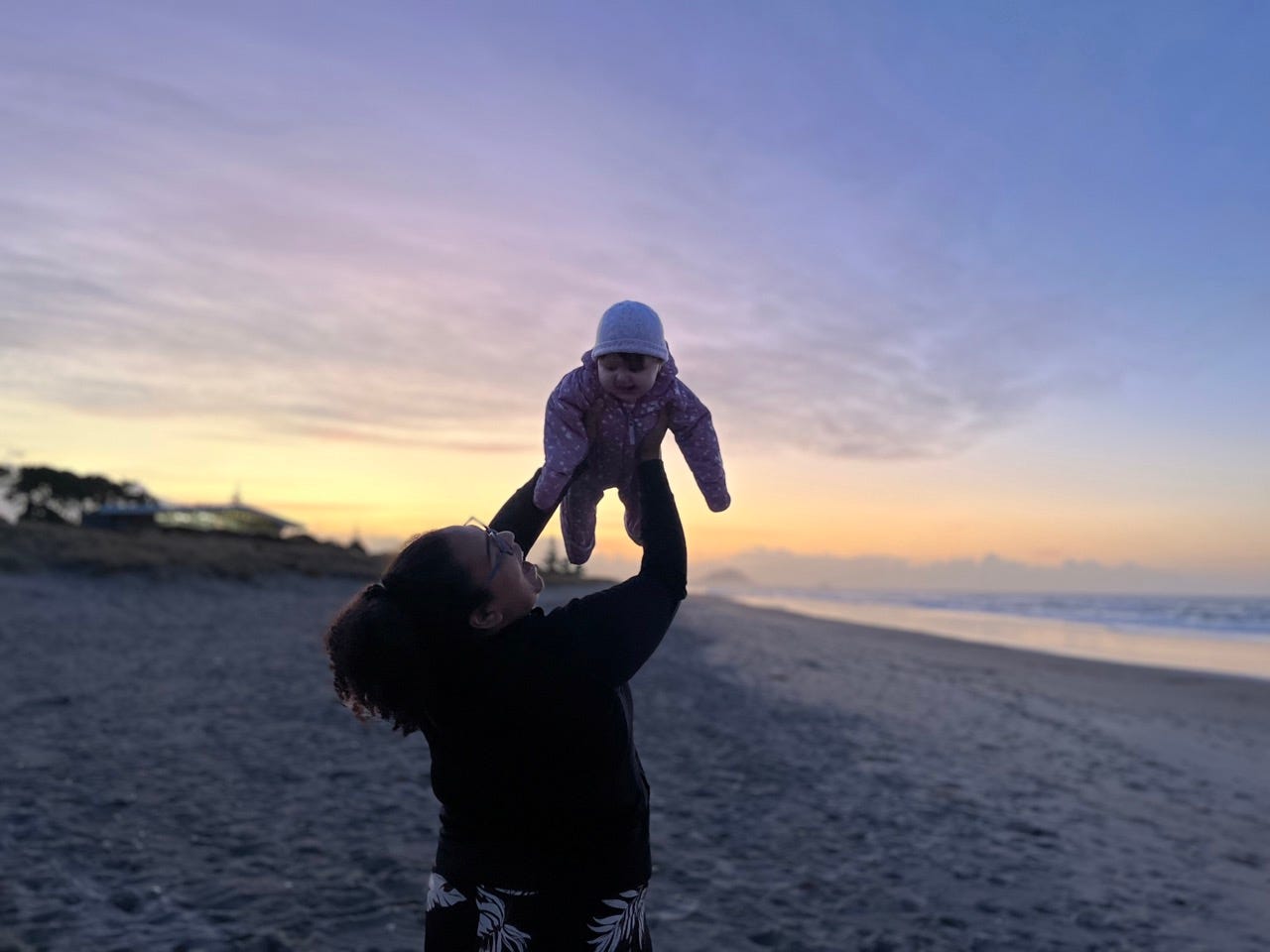 Author Alejandra Rojas holding her baby in the air at the beach