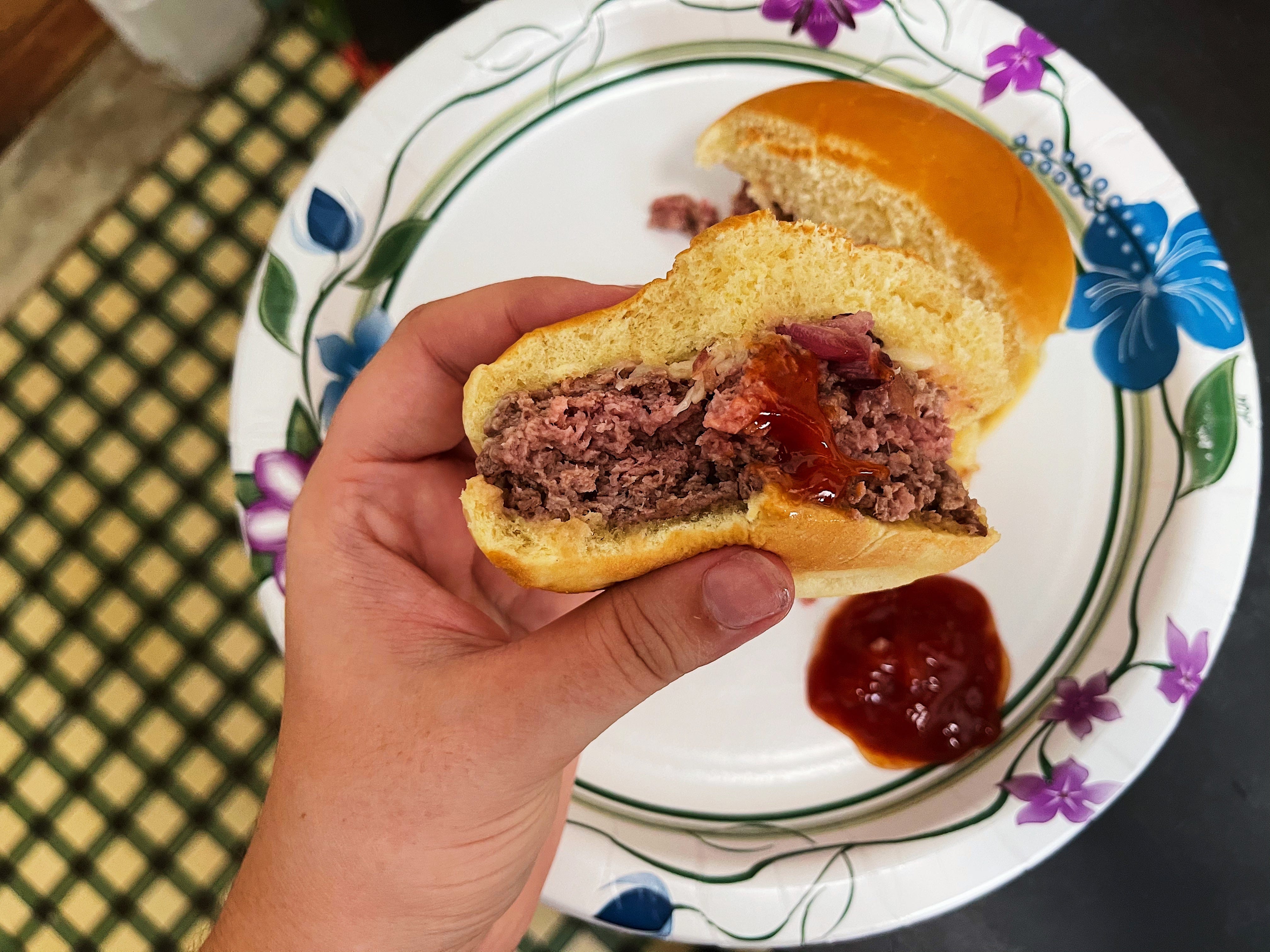 a person holding half of a burger