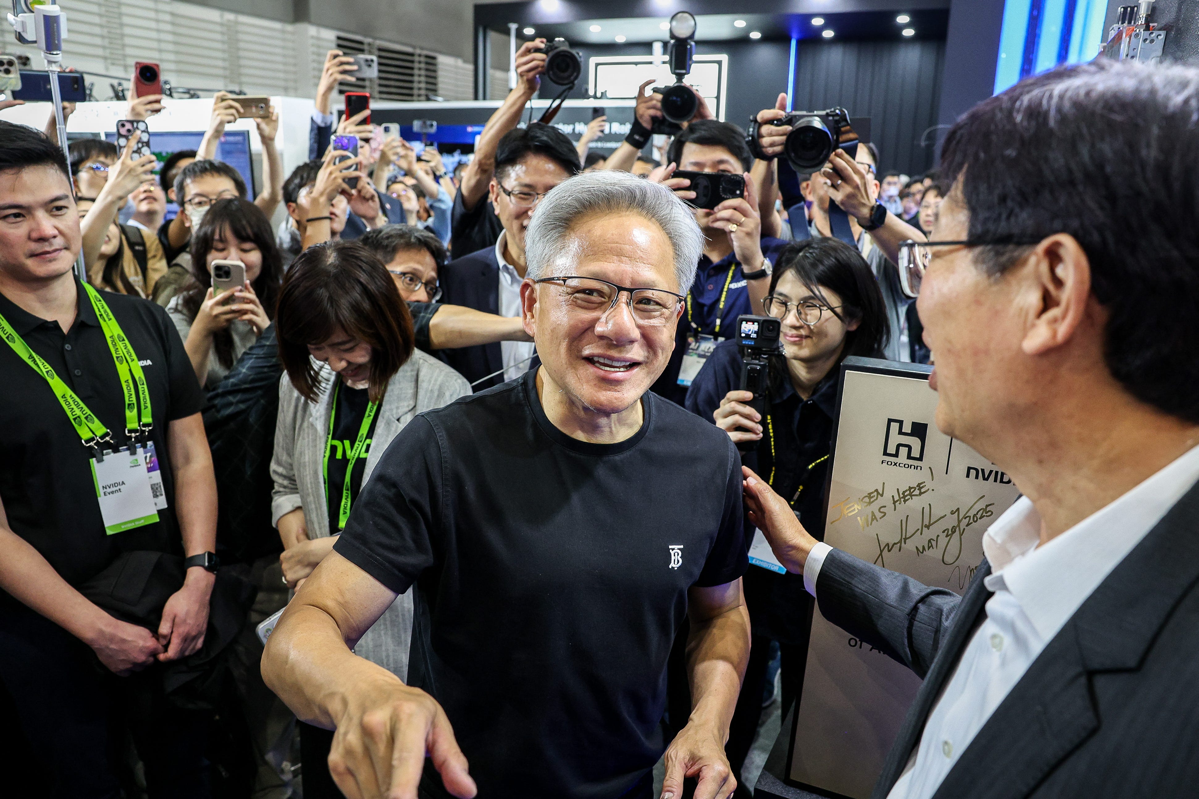 Nvidia CEO Jensen Huang surrounded by a group of excited fans and press in Taiwan.