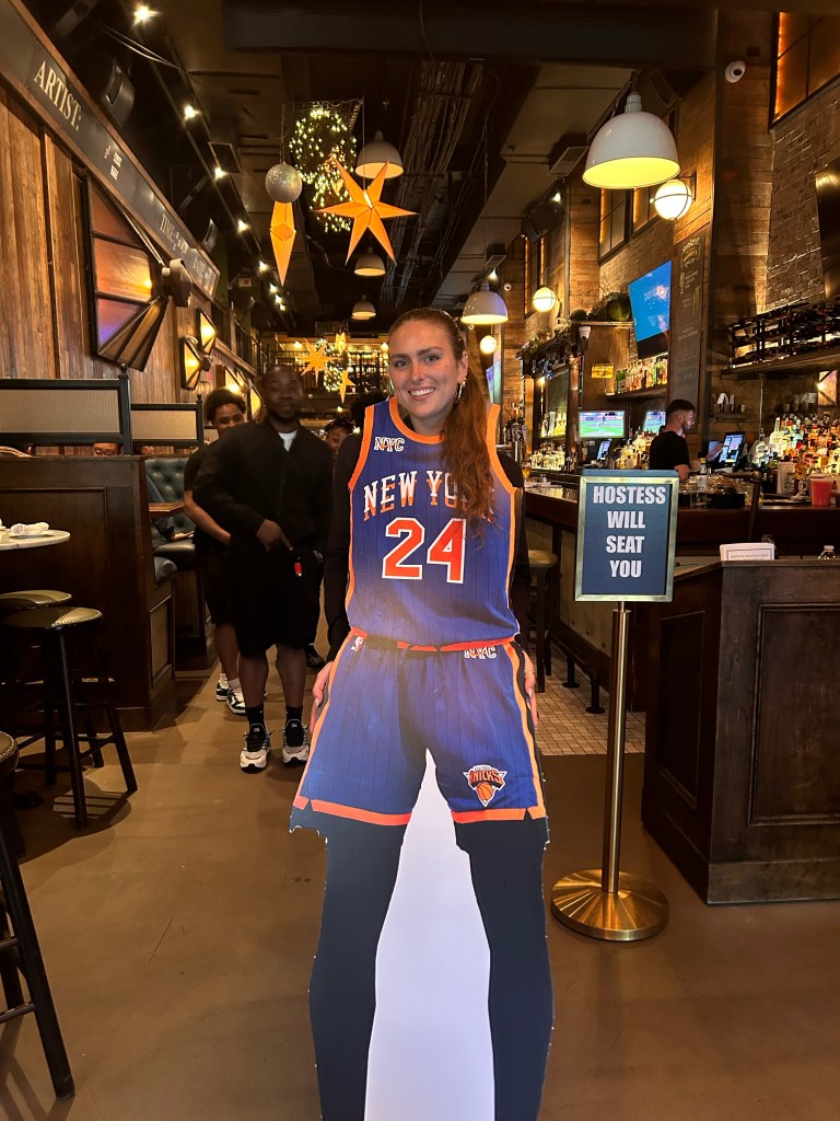 A fan uses a cardboard cut out of a basketball player.