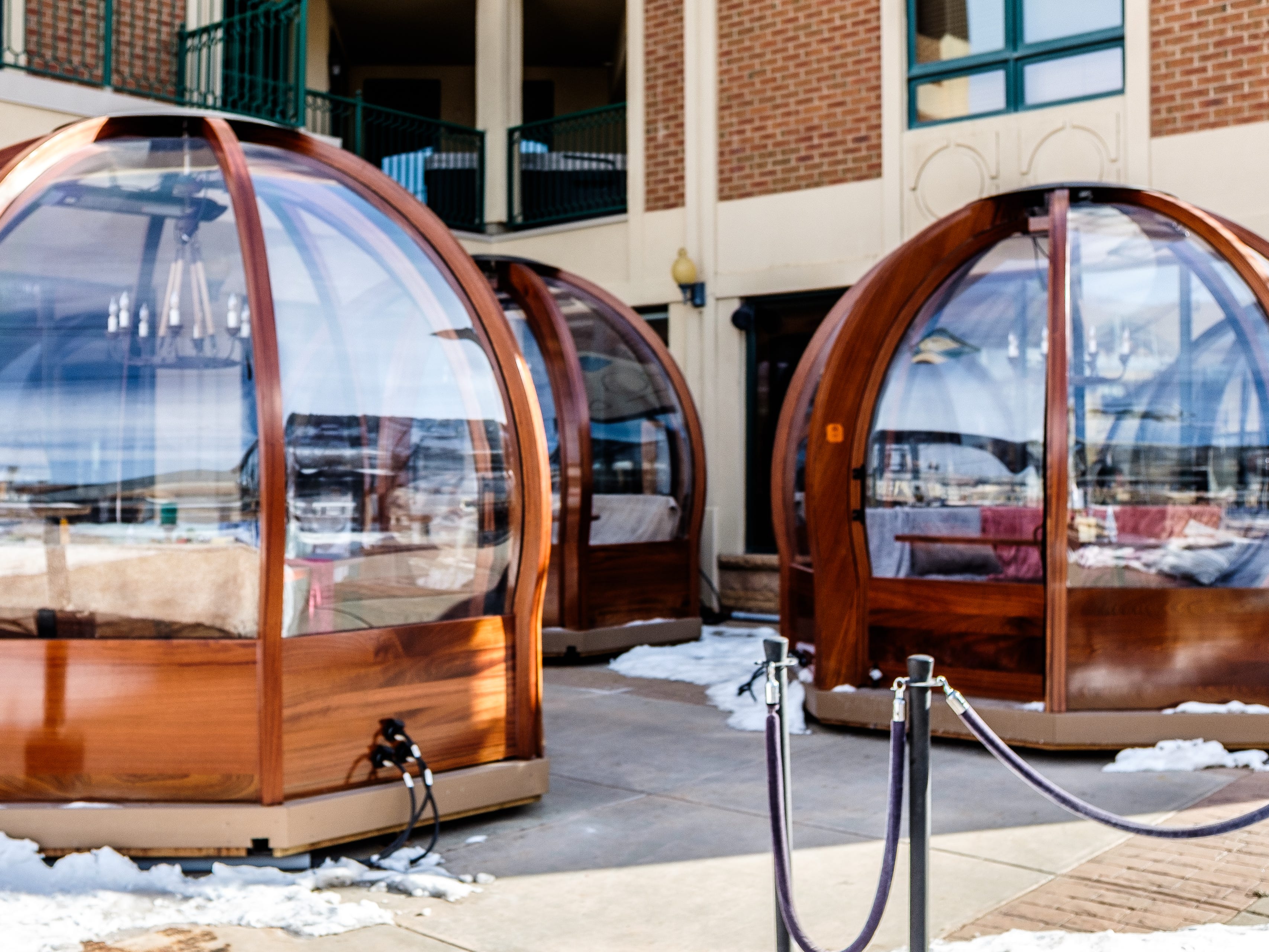 Three enclosed dining globes in an outdoor courtyard with snow on the ground