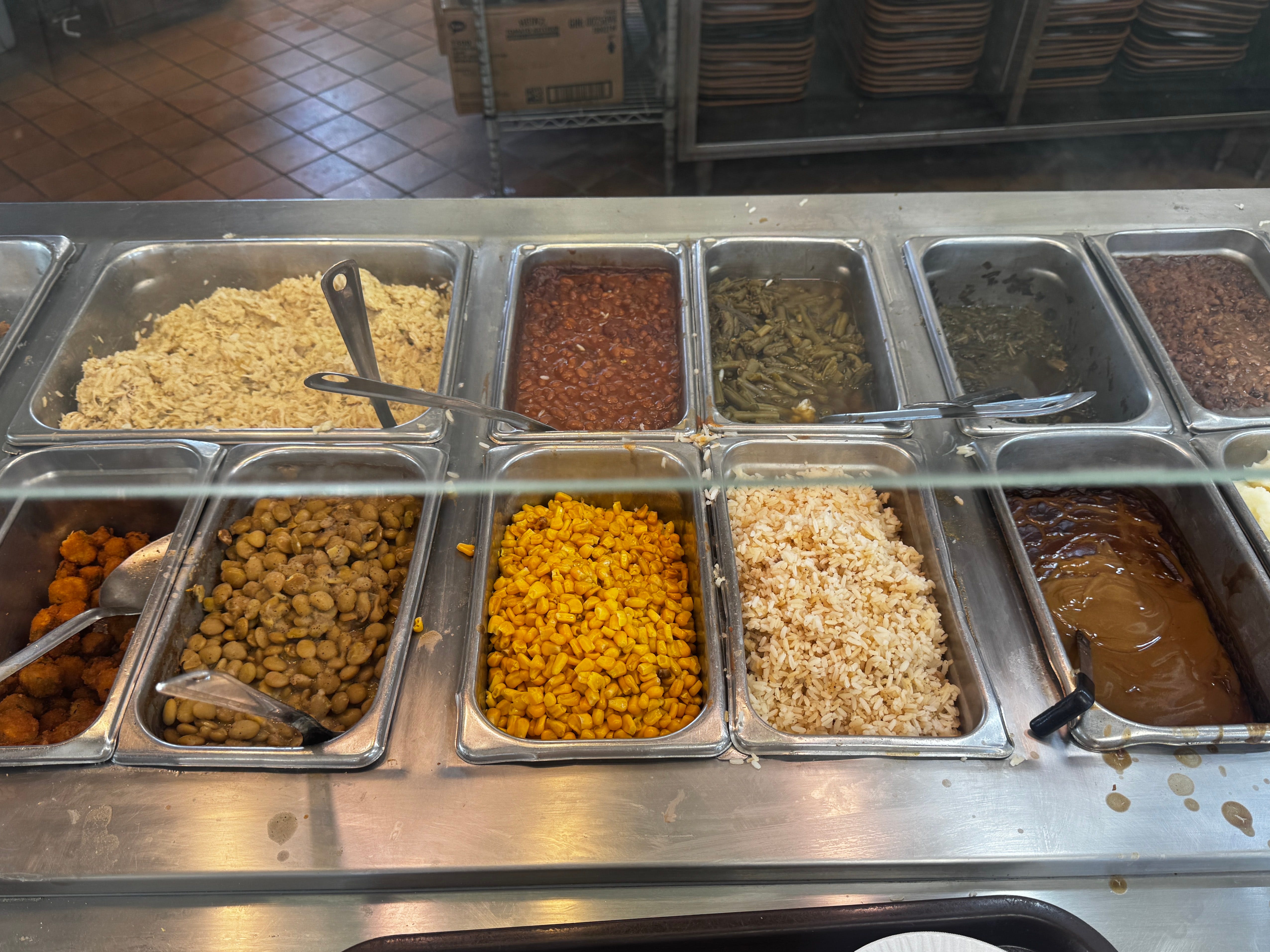 A buffet with selections like beans, corn, greens, rice, and gravy.