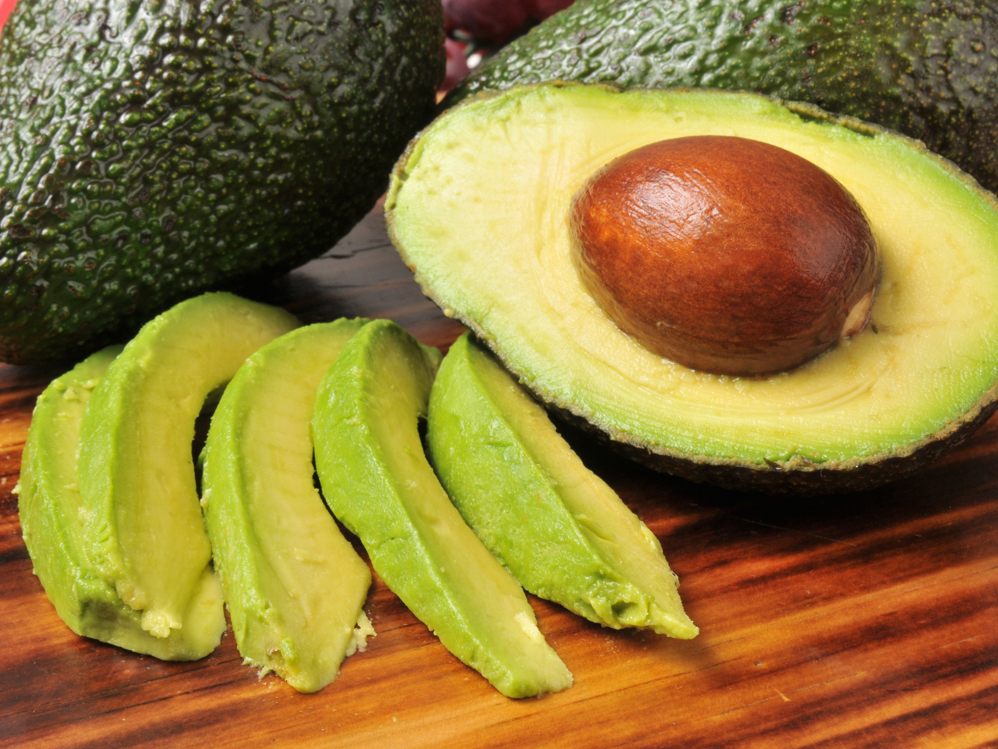 half of an avocado and slices of avocado
