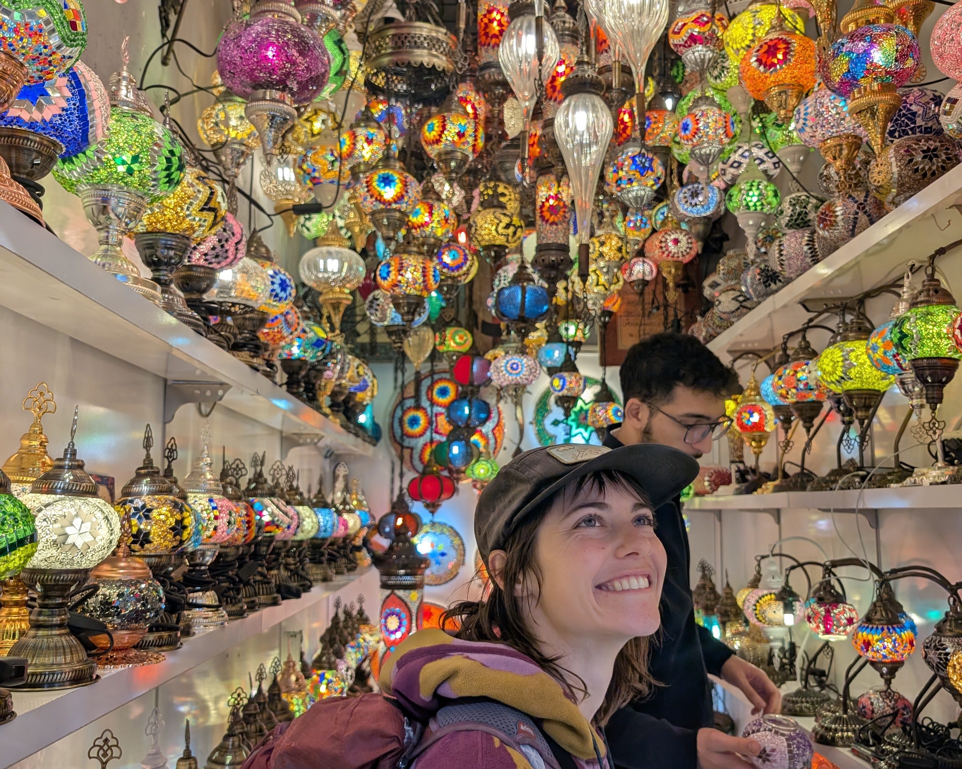 Woman smiling inside Grand Bazaar with colorful lamps above
