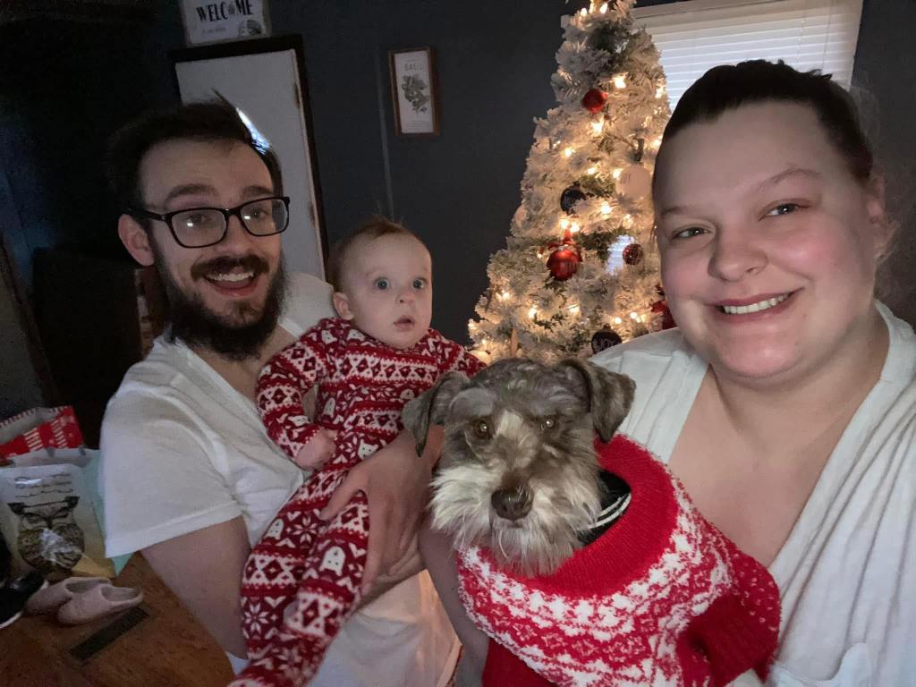 The Hollifield family posing with their rescued mini schnauzer, Newt, after a tornado.