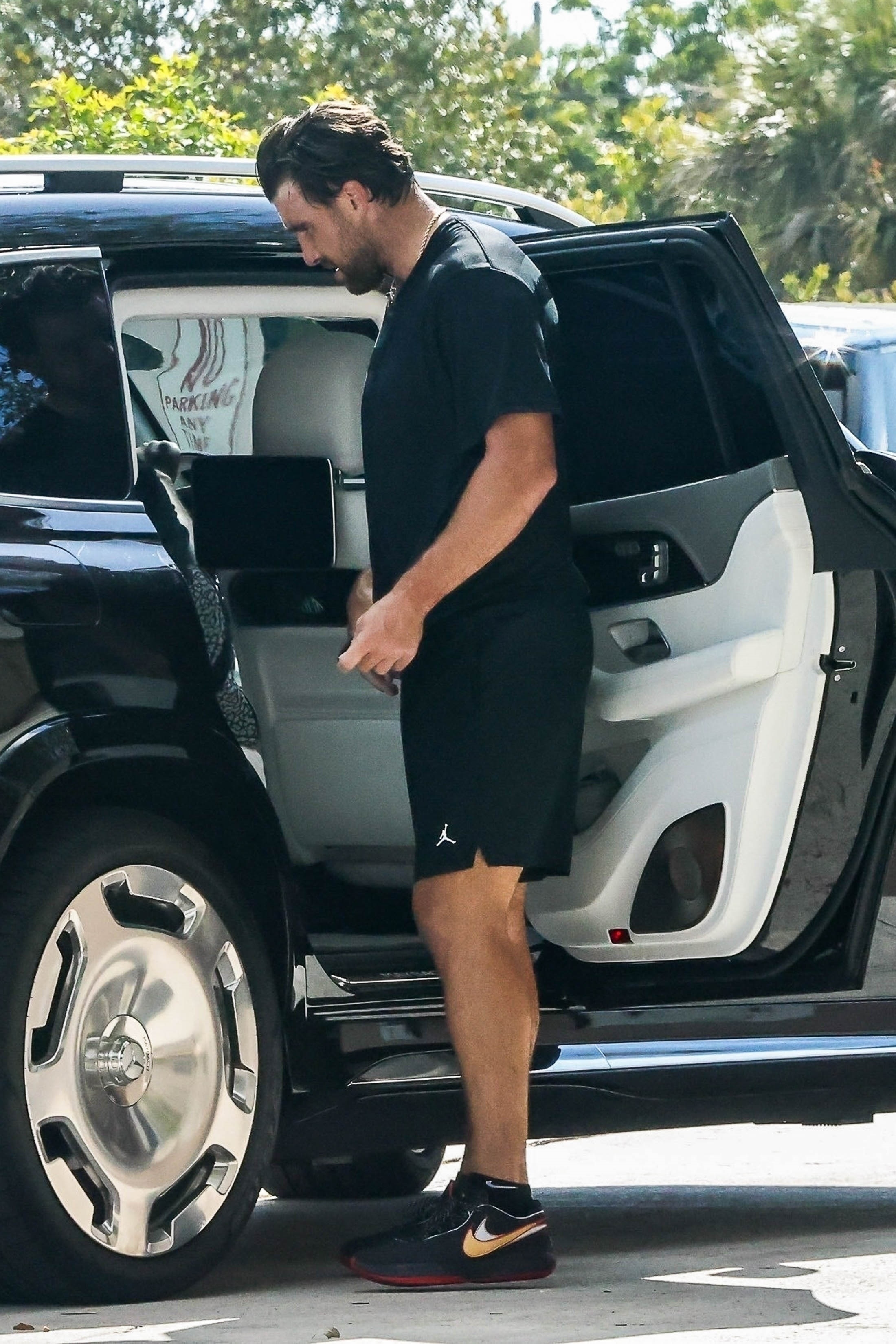 Travis Kelce wears a black shirt outdoors. 