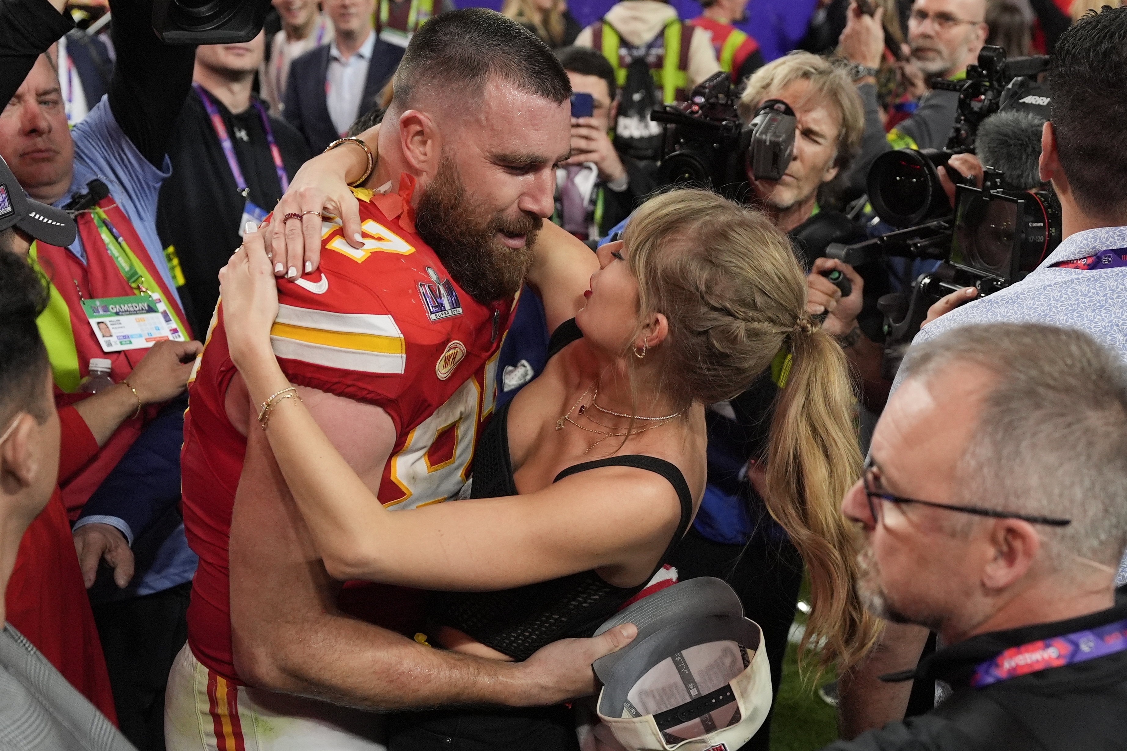 Taylor Swift hugs Travis Kelce on a football field. 
