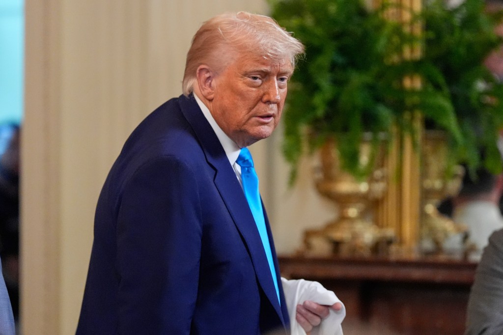 President Donald Trump holding a jersey while departing from the East Room of the White House after hosting the 2025 NCAA Champion, University of Florida men's basketball team.