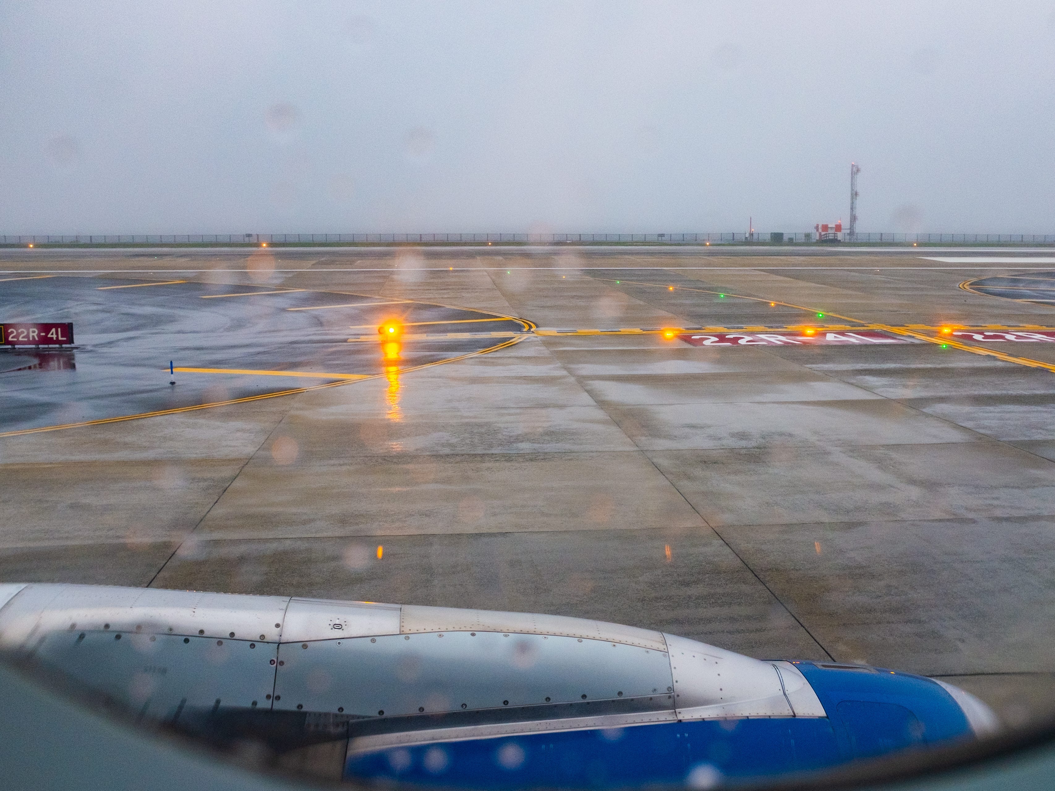 A view out the window of a flight on the tarmac on a rainy day with foggy skies