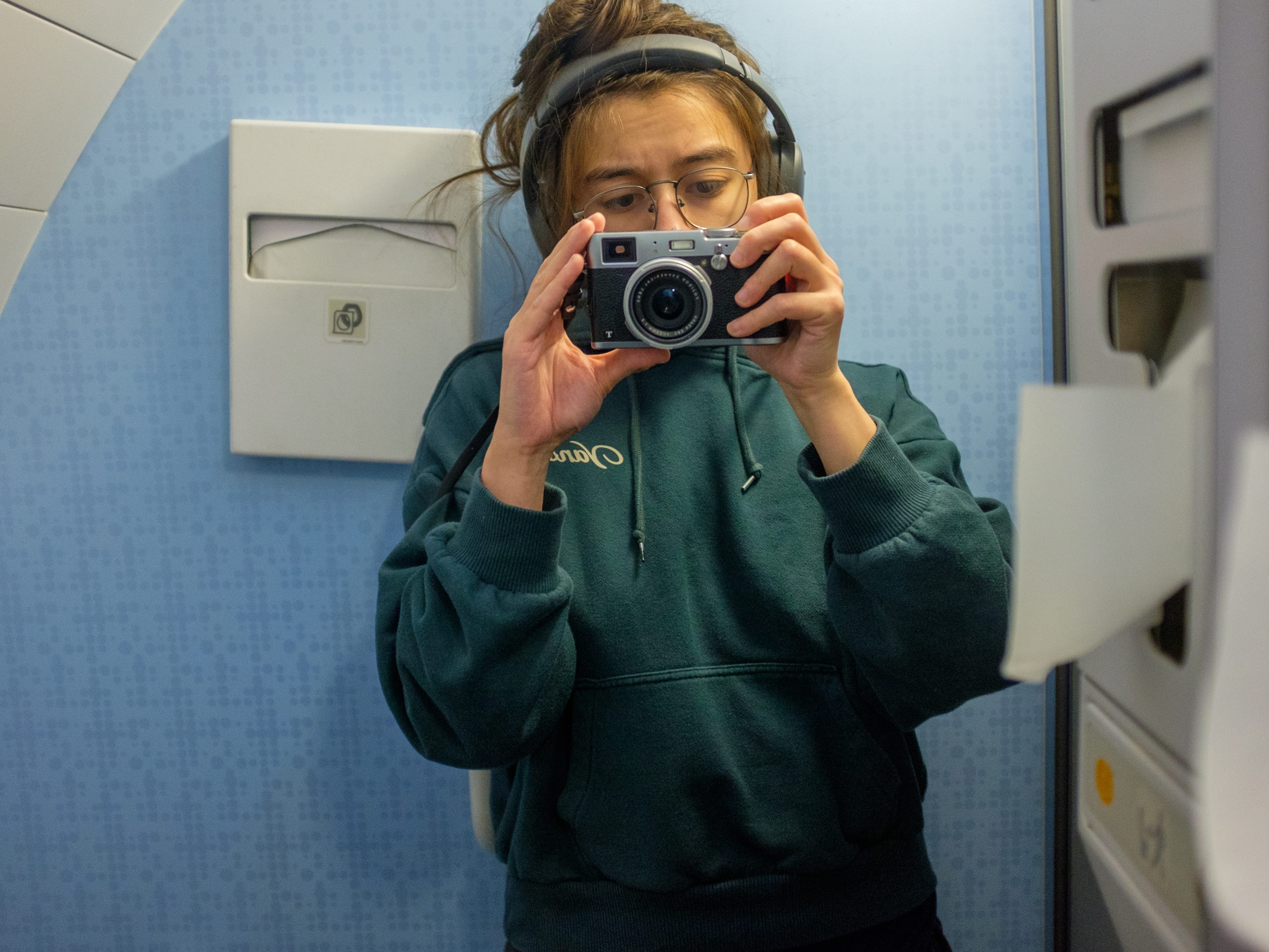 The author takes a mirror selfie with a digital camera in a plane bathroom