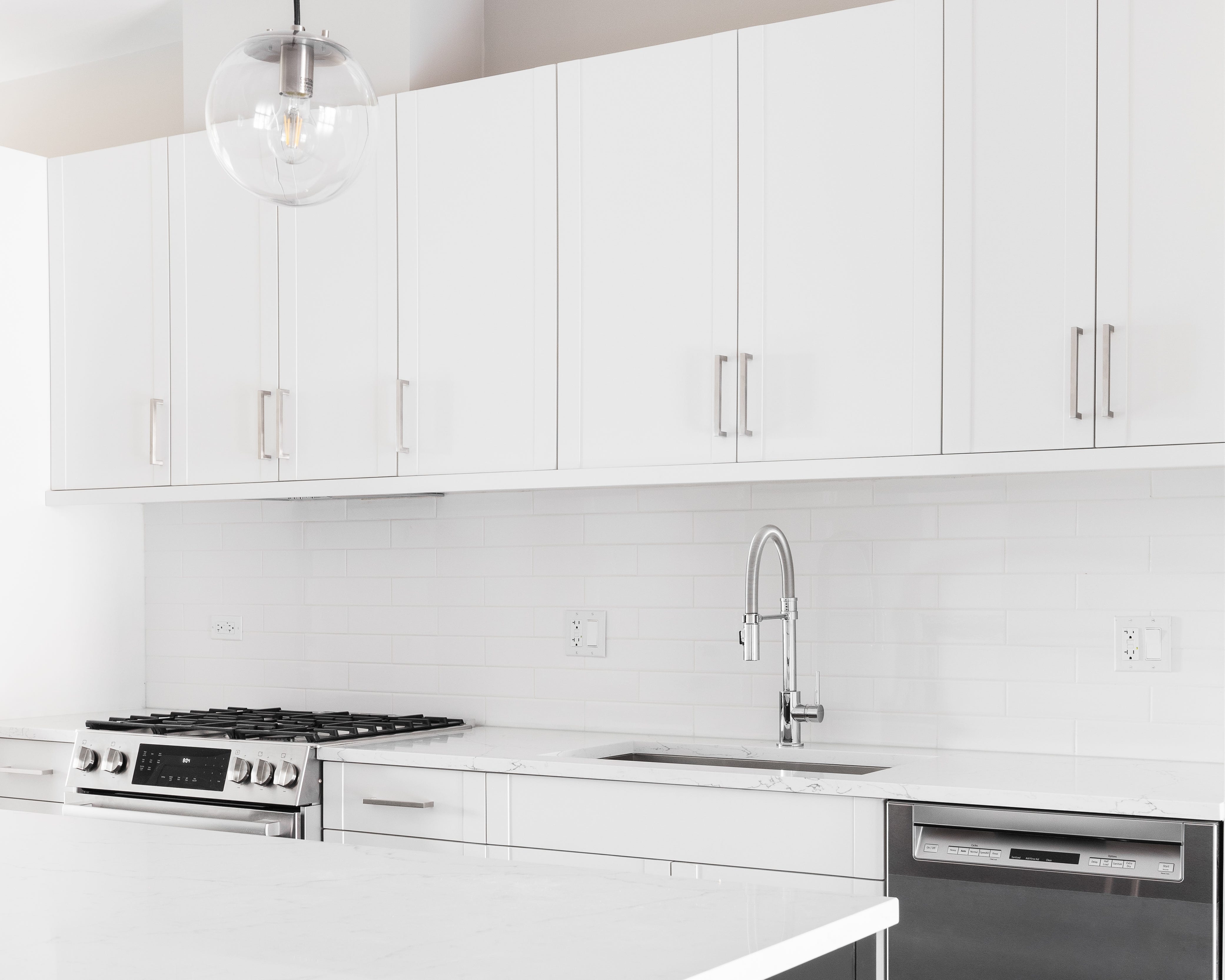 An all-white kitchen with stainless steel appliances.