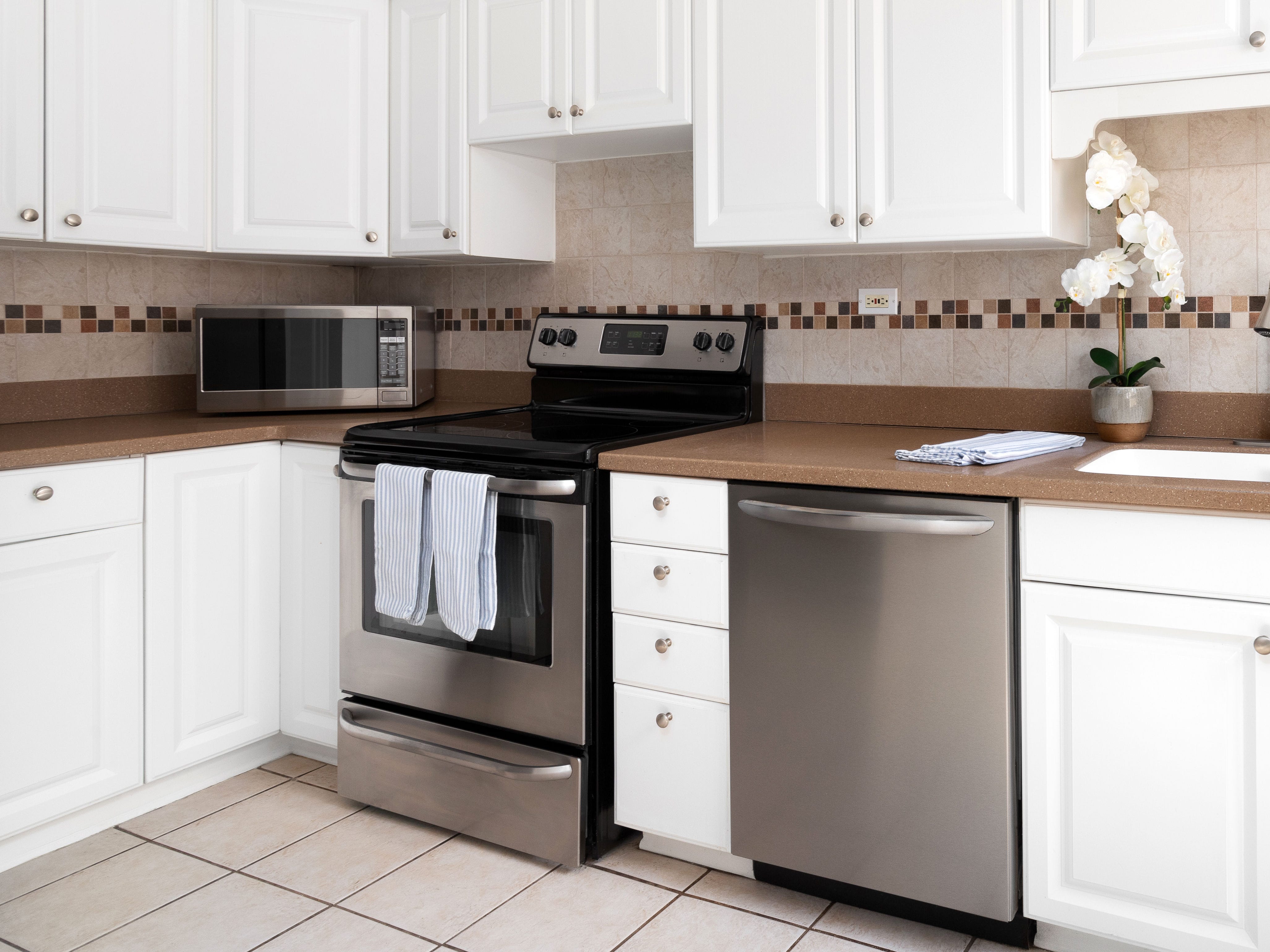 A kitchen with white cabinets and simple silver hardware.