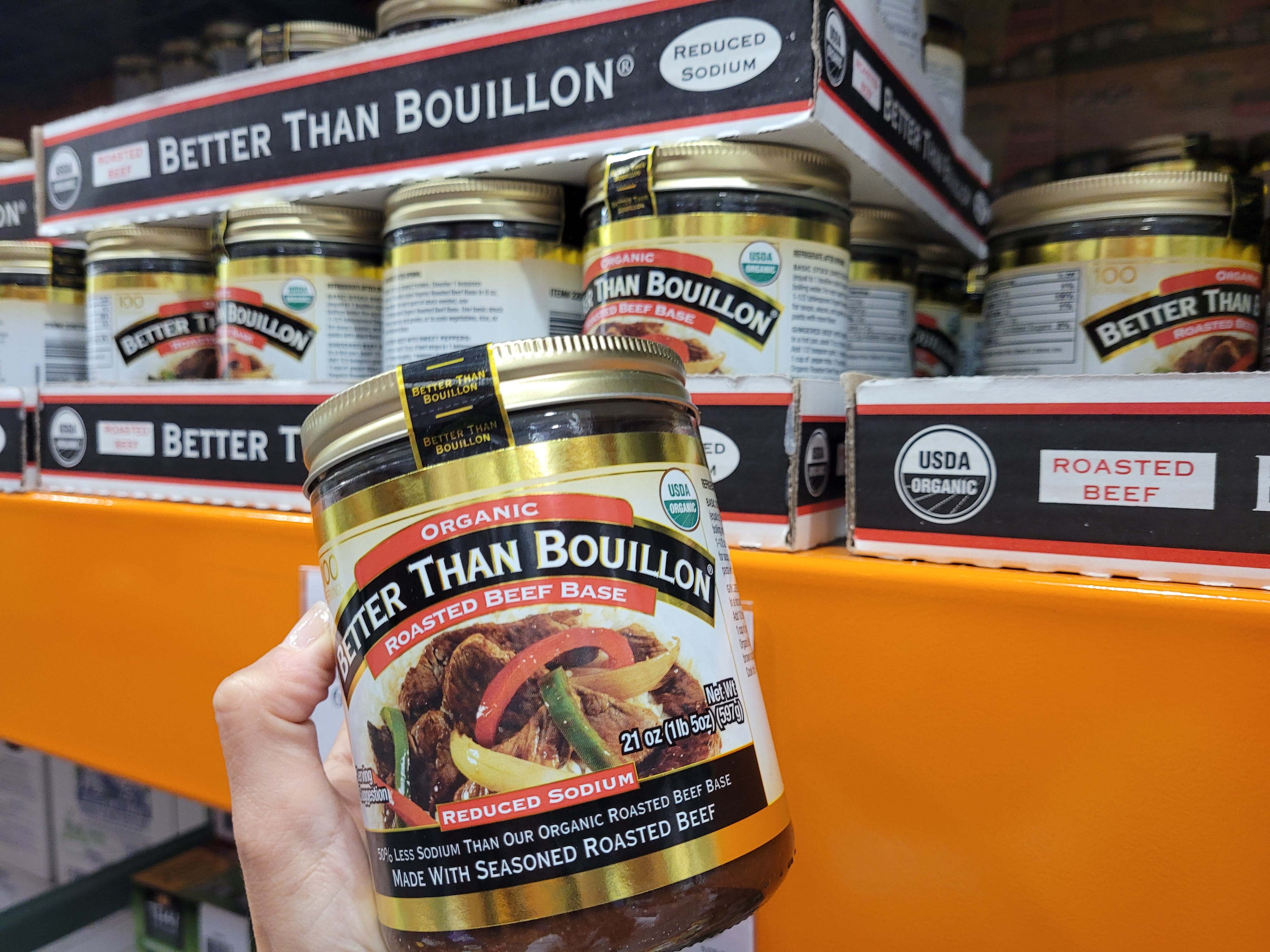 A close-up of the author's hand holding a jar of Better Than Bouillon Roasted Beef Base.