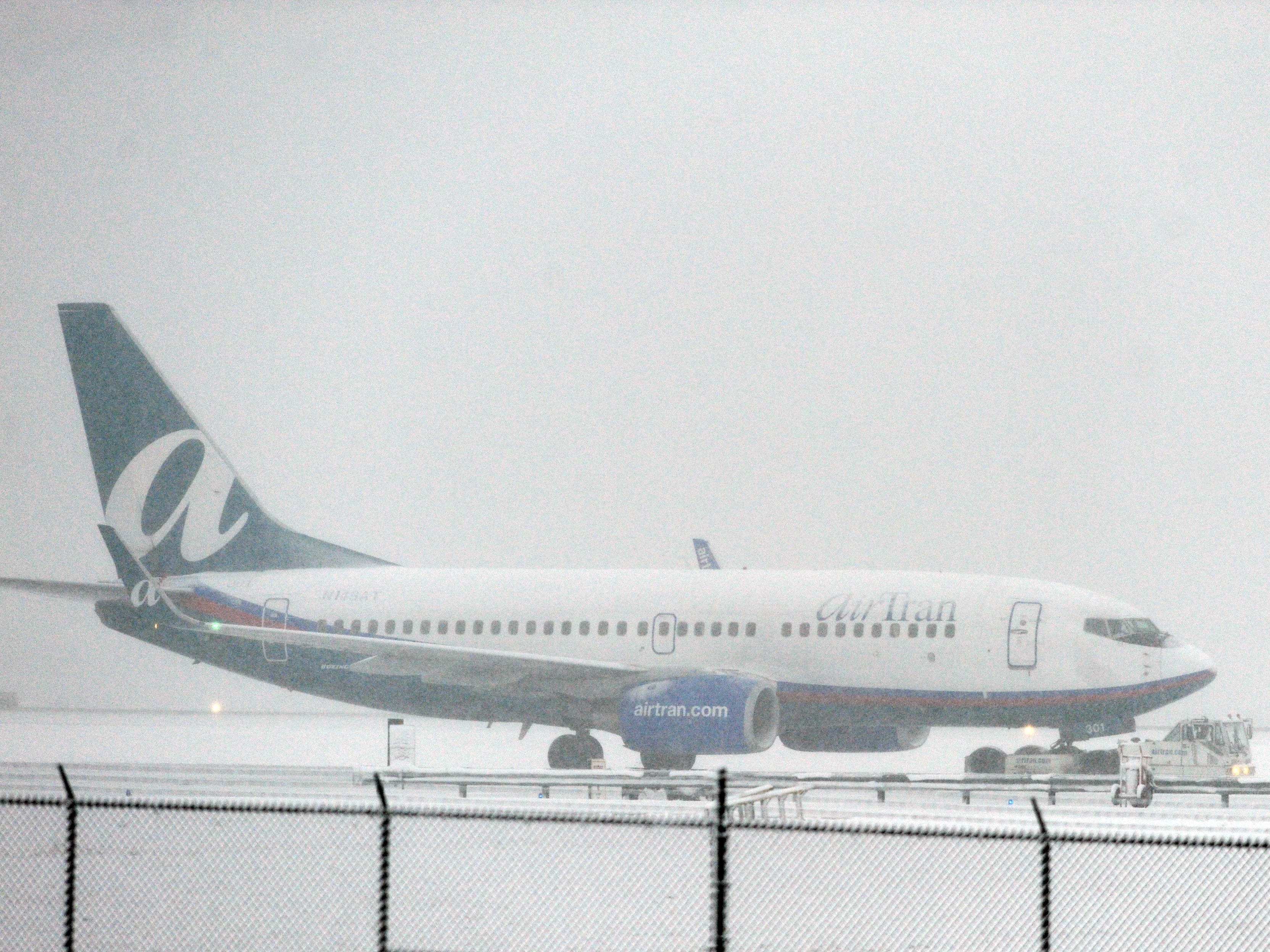 An AirTran Airways jet is pulled along a snowy taxiway at Hartsfield Jackson Atlanta International Airport in Atlanta.