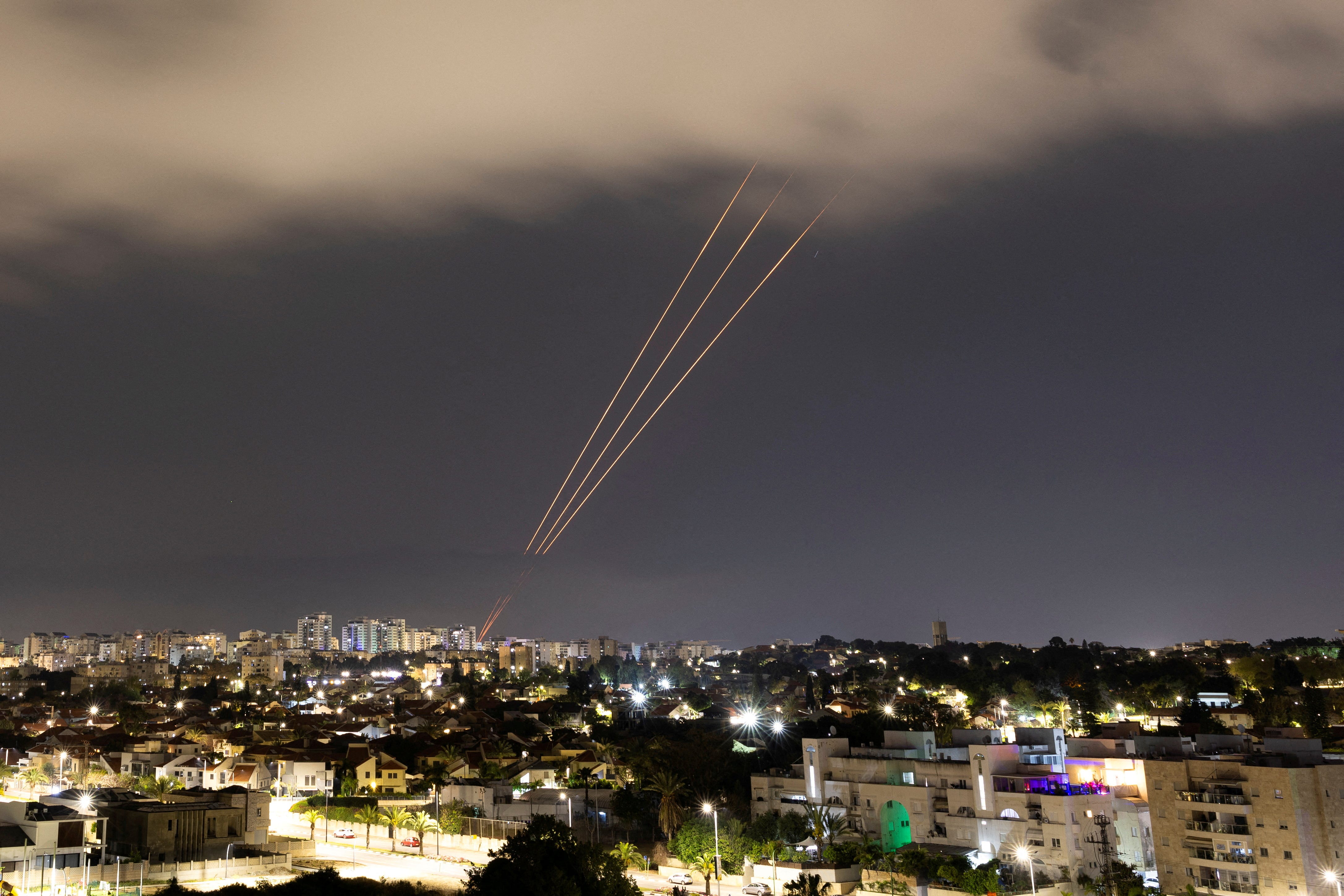 An anti-missile system beaming lines of light into the night sky over a city.
