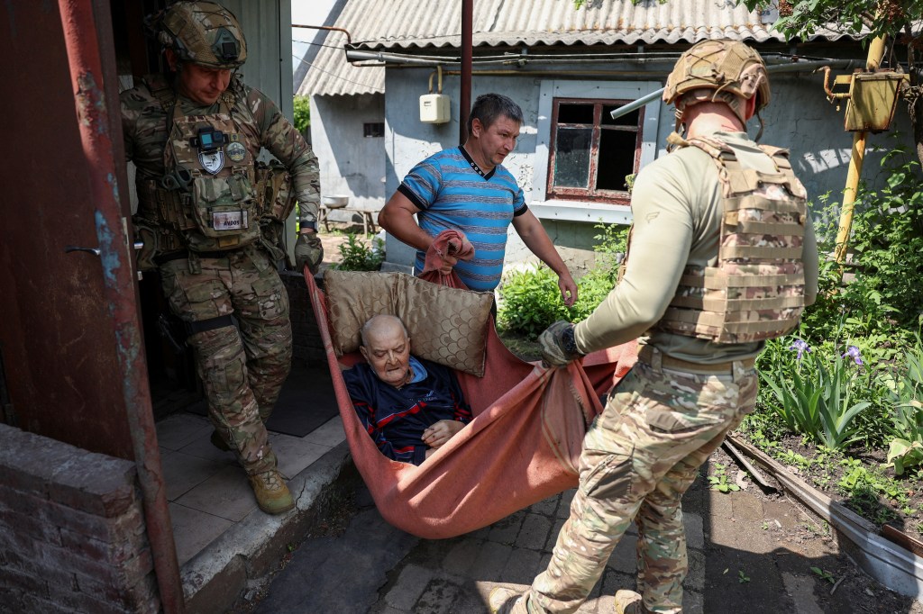 Ukrainian police officers from the White Angel unit evacuating an elderly man from his house in the frontline town of Pokrovsk