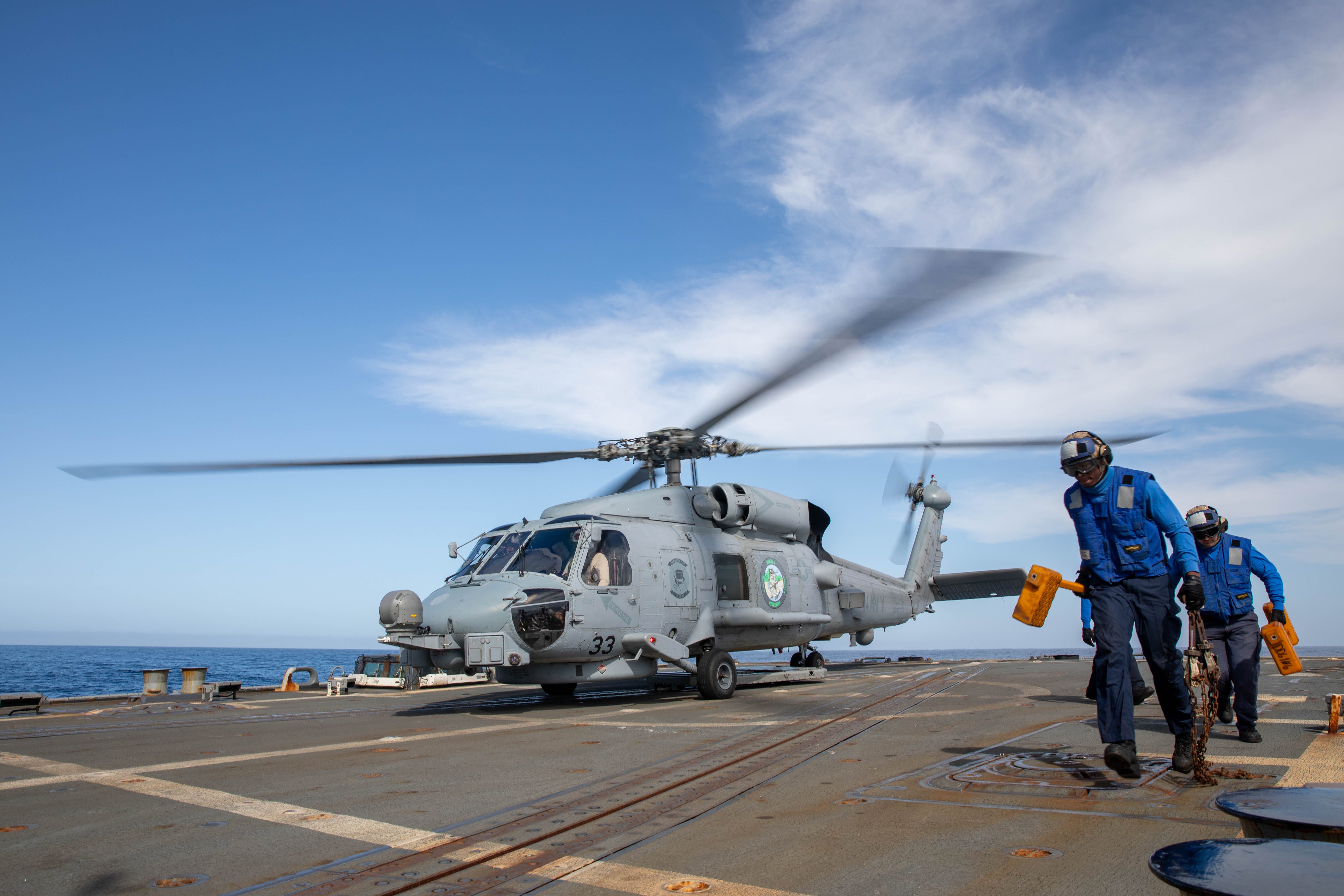 Sailors assigned to the Arleigh Burke-class guided-missile destroyer USS Stockdale (DDG 106), transit the flight deck after removing chocks and chains from an MH-60R, assigned to the "Magicians" of Helicopter Maritime Strike Squadron (HSM) 35, while underway in the Pacific Ocean, April 11, 2025.
