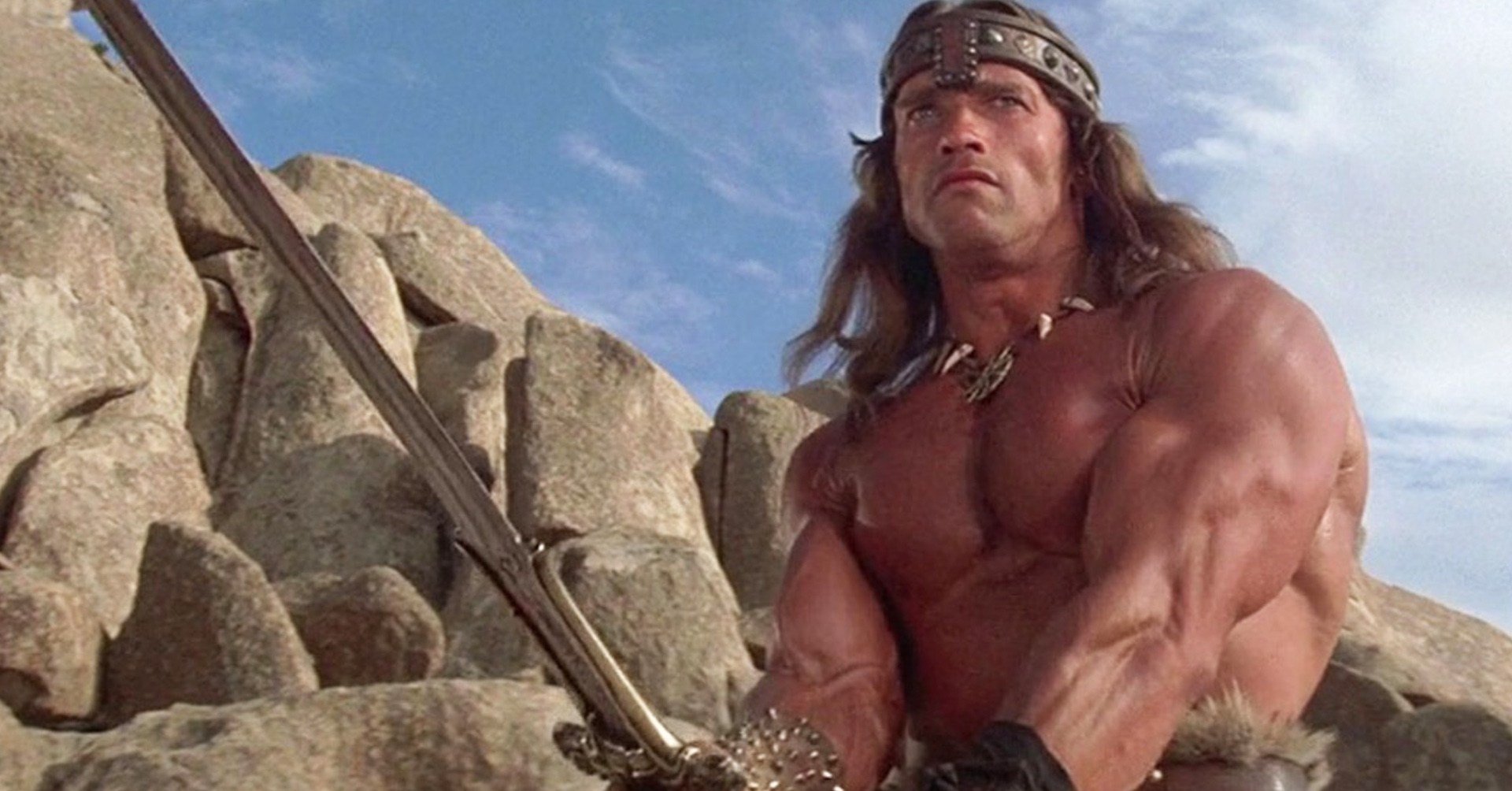 An extremely buff man wields a sword.