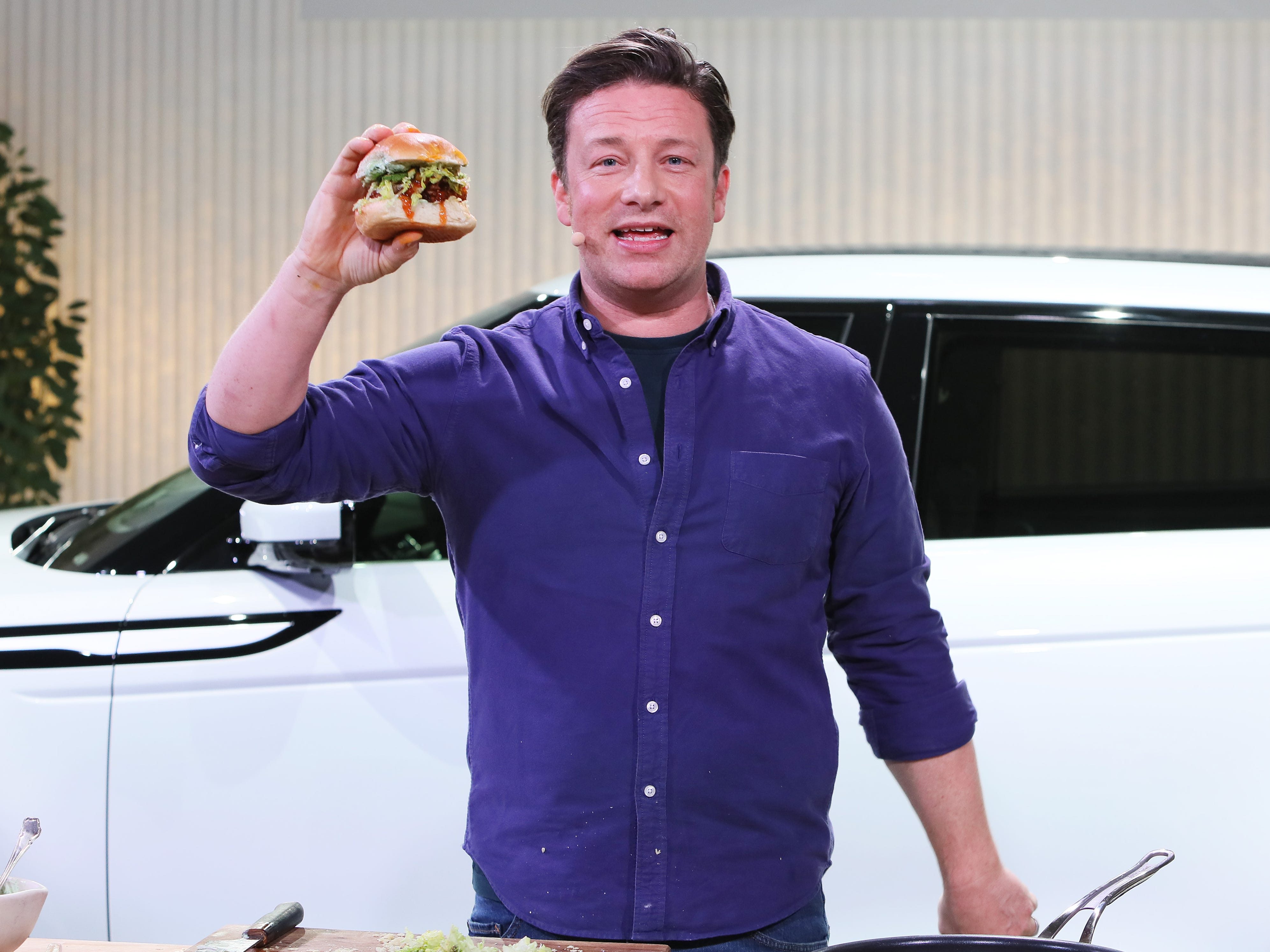 Jamie Oliver holding up a burger