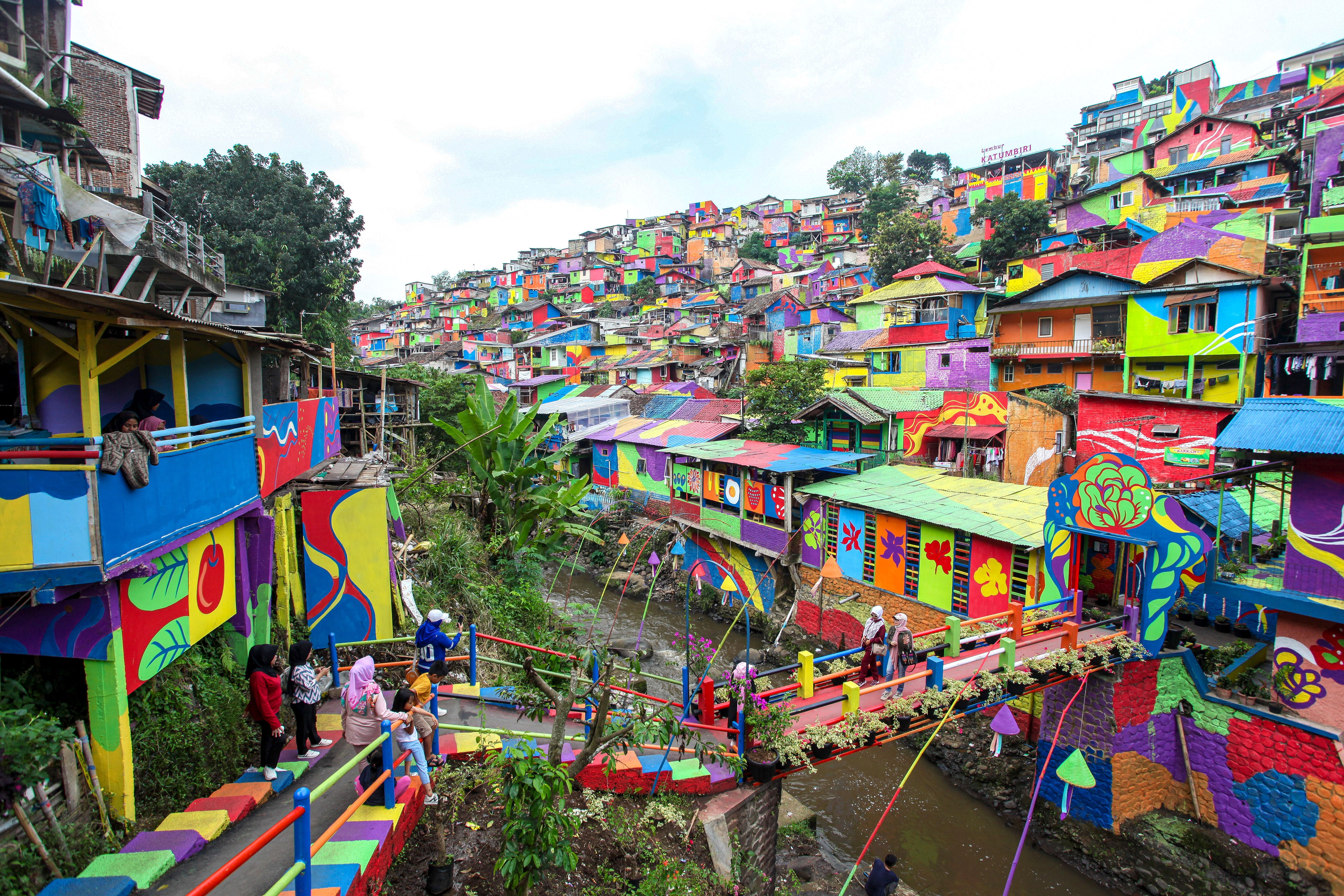 Many houses sit in a hillside neighborhood, all painted in verying bright colors.